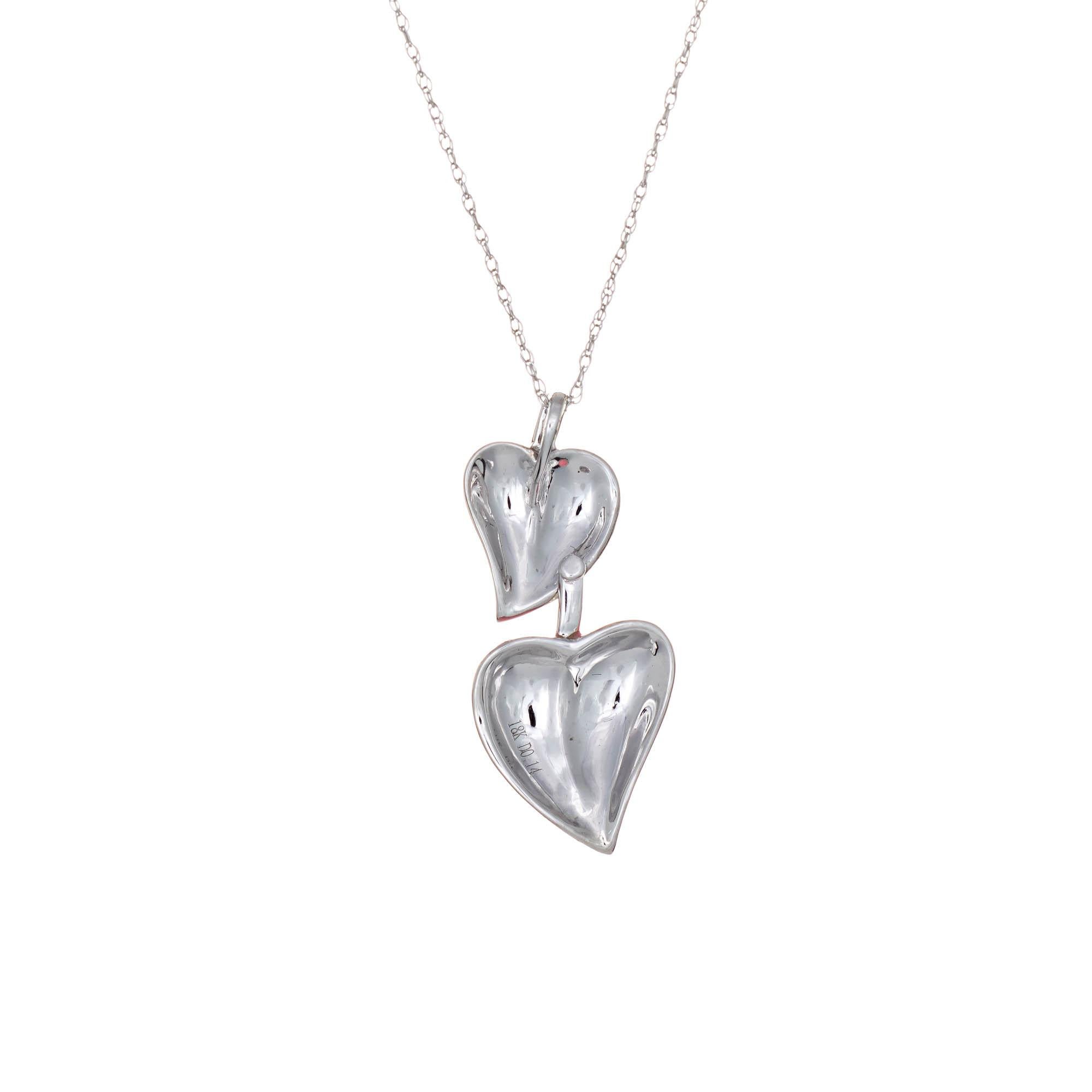 Stylish double heart diamond necklace crafted in 18 karat white gold.  

Diamonds total an estimated 0.14 carats (estimated at G-H color and SI1 clarity). 

The double heart design features a smaller heart set with orange enamel and the larger heart