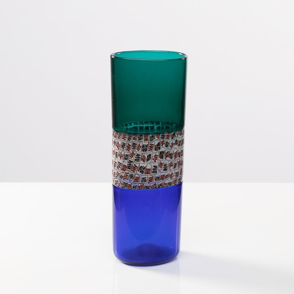 Double incalmo e murrina Riccardo Licata - Vase en verre soufflé - Venini Murano.
Vase à section irrégulière et aplatie en verre transparent double incalmo bleu et vert.
Bandeau central en verre clair décoré de murrines à décor rouge et noir.
A