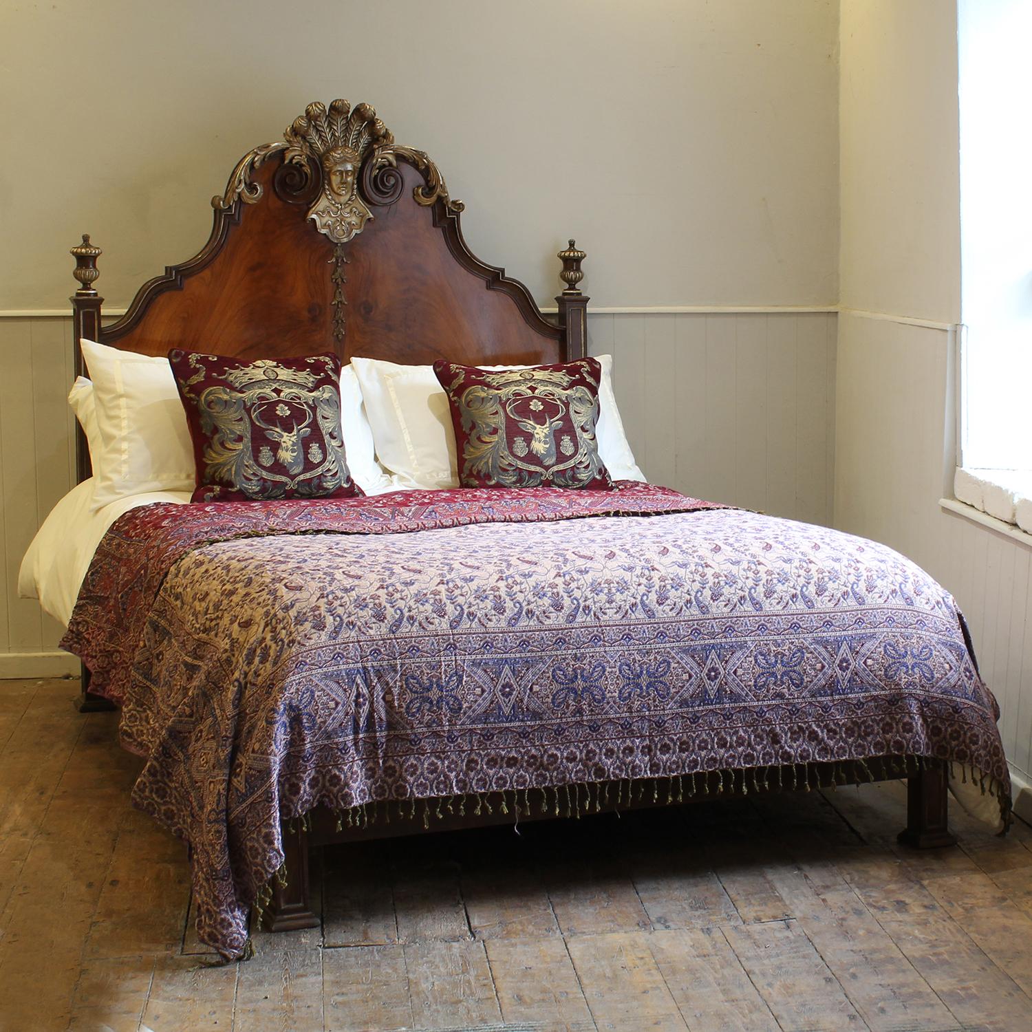 Fabulosa cama doble de plataforma italiana con cabecero alto de nogal con paneles de rebabas, remates en forma de urna y frontón tallado con el rostro de una dama y una corona de plumas, todo ello resaltado en un tono plateado/dorado.

Esta cama