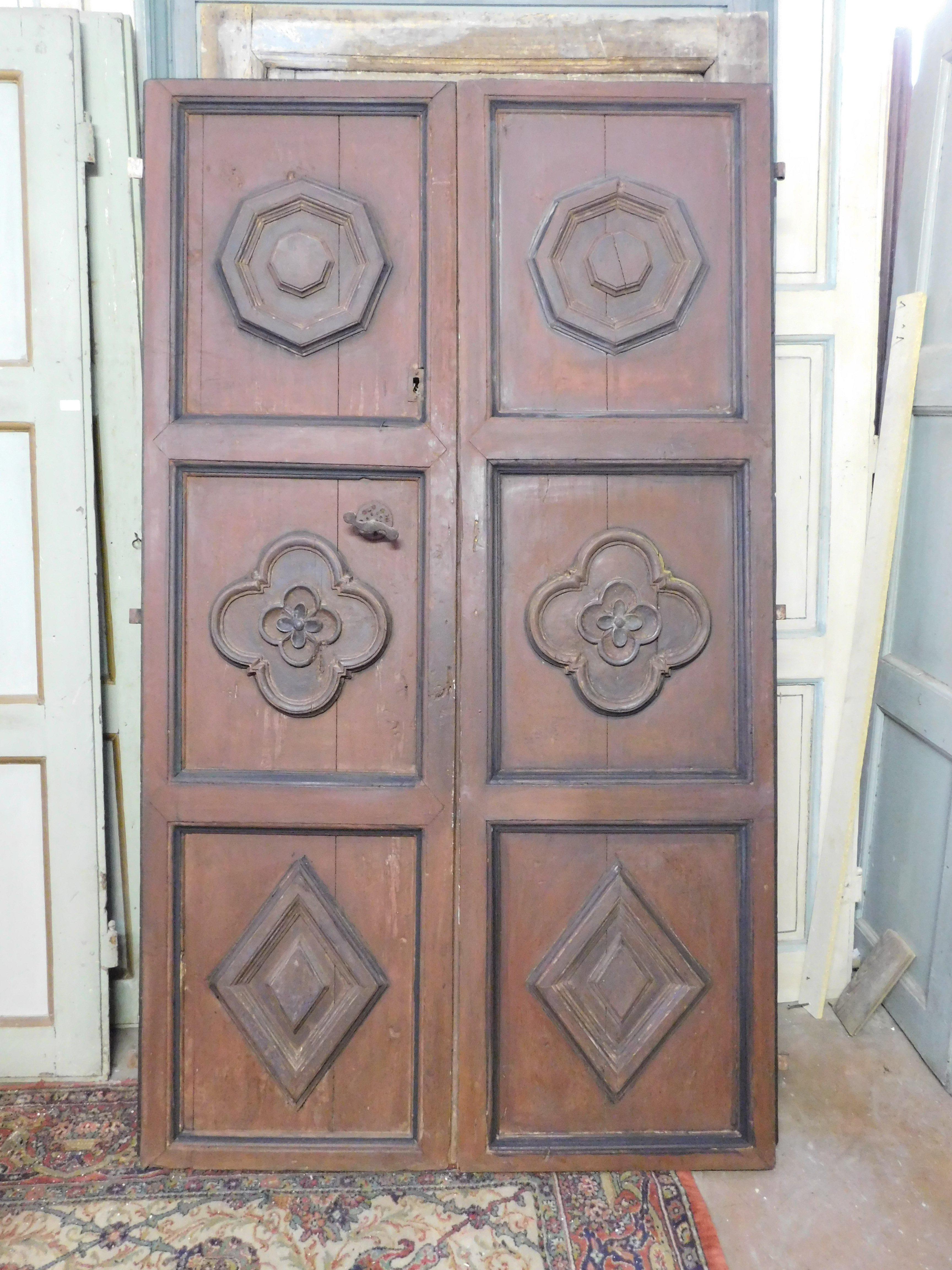 Pequeña puerta antigua (adaptable como puerta interior y como puerta de entrada), compuesta por dos puertas lacadas en rojo pompeyano y con rosetas talladas en el interior de los paneles, trasera de madera lisa con bandas horizontales. Original del