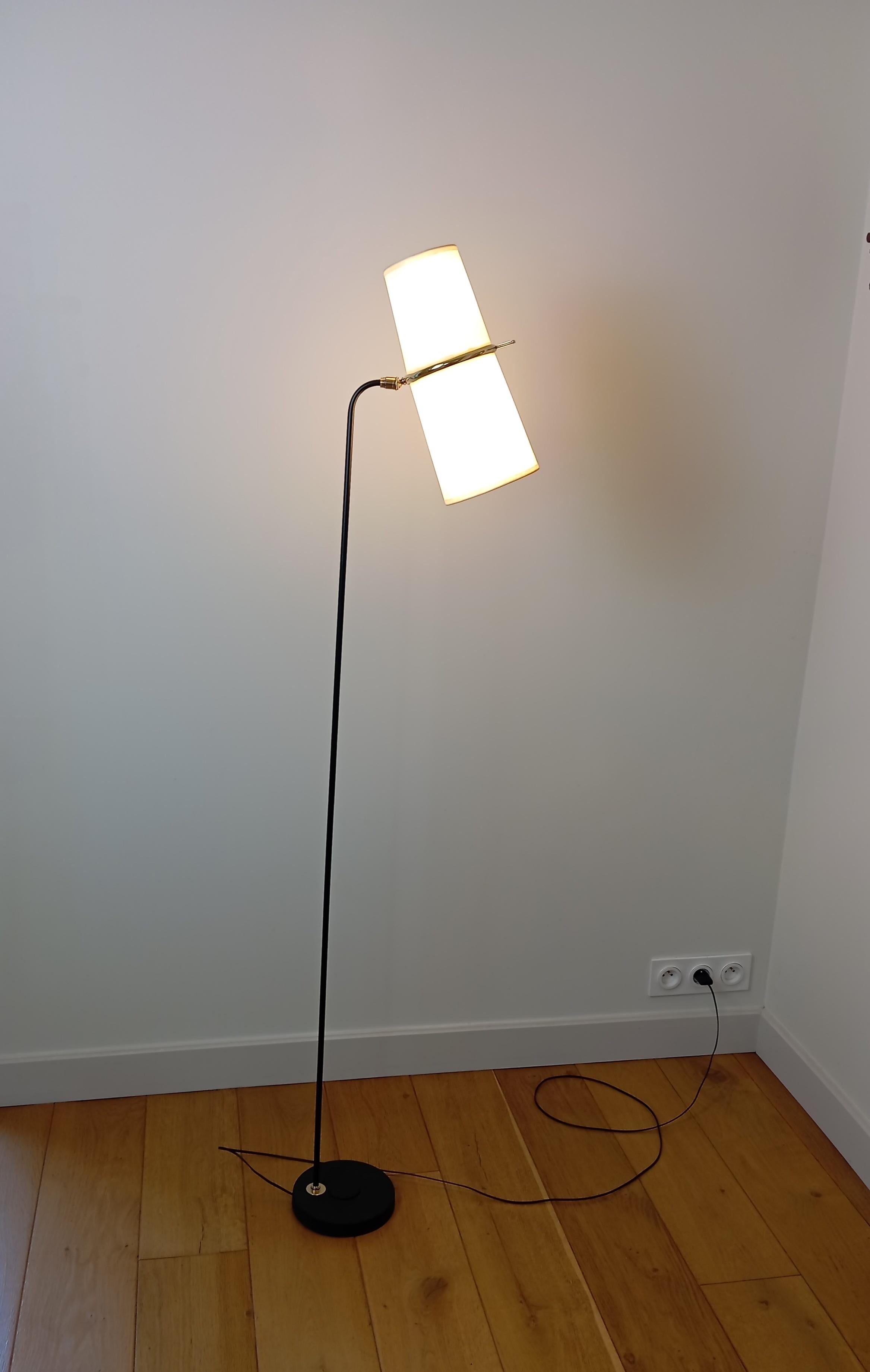 Black lacquered metal and brass floor lamp;
composed of a circular black lacquered cast iron base, to which is attached a black lacquered metal arm, ending in a brass support holding two slightly conical shades.
Double lighting adjustable by a brass