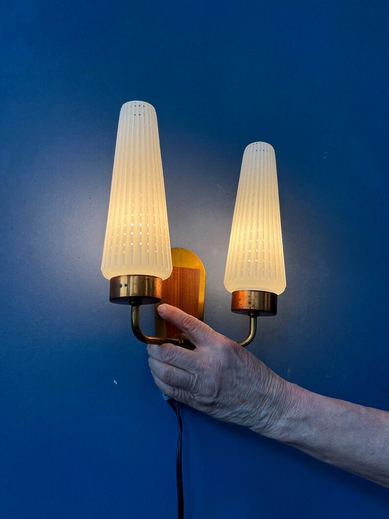 Aplique doble escandinavo de mediados de siglo con dos pantallas de cristal. El marco de la luminaria tiene elementos de madera y latón. La lámpara necesita dos bombillas E14 y actualmente tiene un enchufe UE.

Más información:
Materiales: Vidrio,