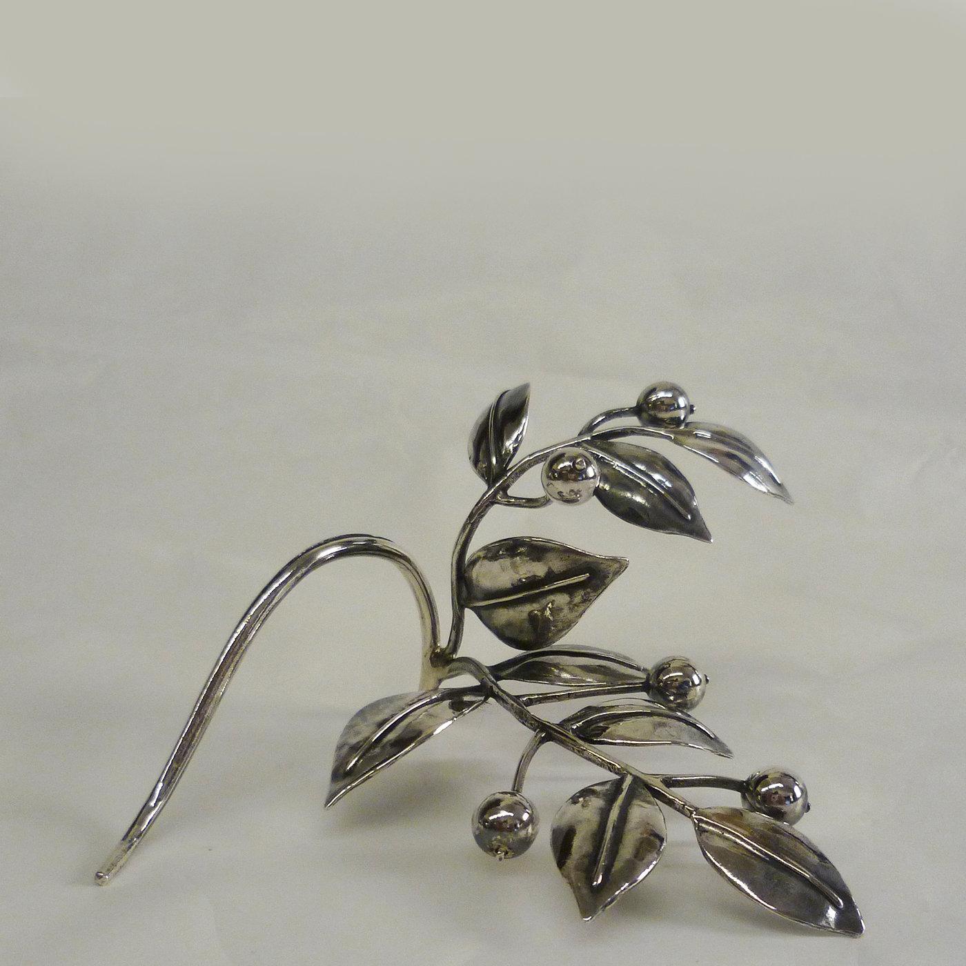 Made of silver and boasting exquisite craftsmanship, this stunning object of functional decor will add a delicate holiday touch to an elegant dinner table. Shaped as a double mistletoe branch, this piece will create a subtle decoration, while also