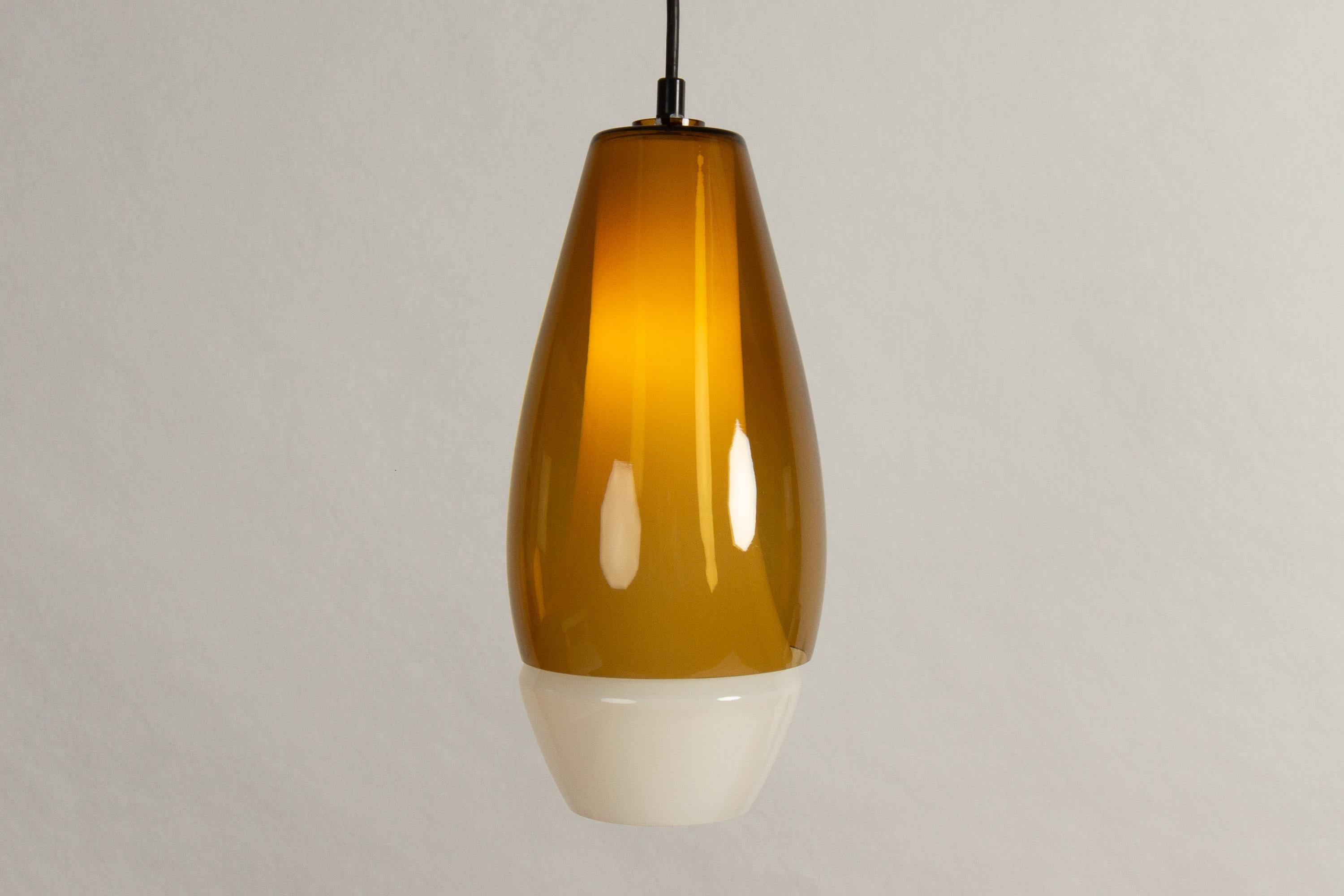 Double mouth-blown glass pendant by Bent Nordsted for Fog & Mørup, 1960s.
Beautiful large Mid-Century Modern oval glass lamp with two shades. Inner shade in white opaline glass. Outer shade in amber colored glass. Emits very warm and soft light.