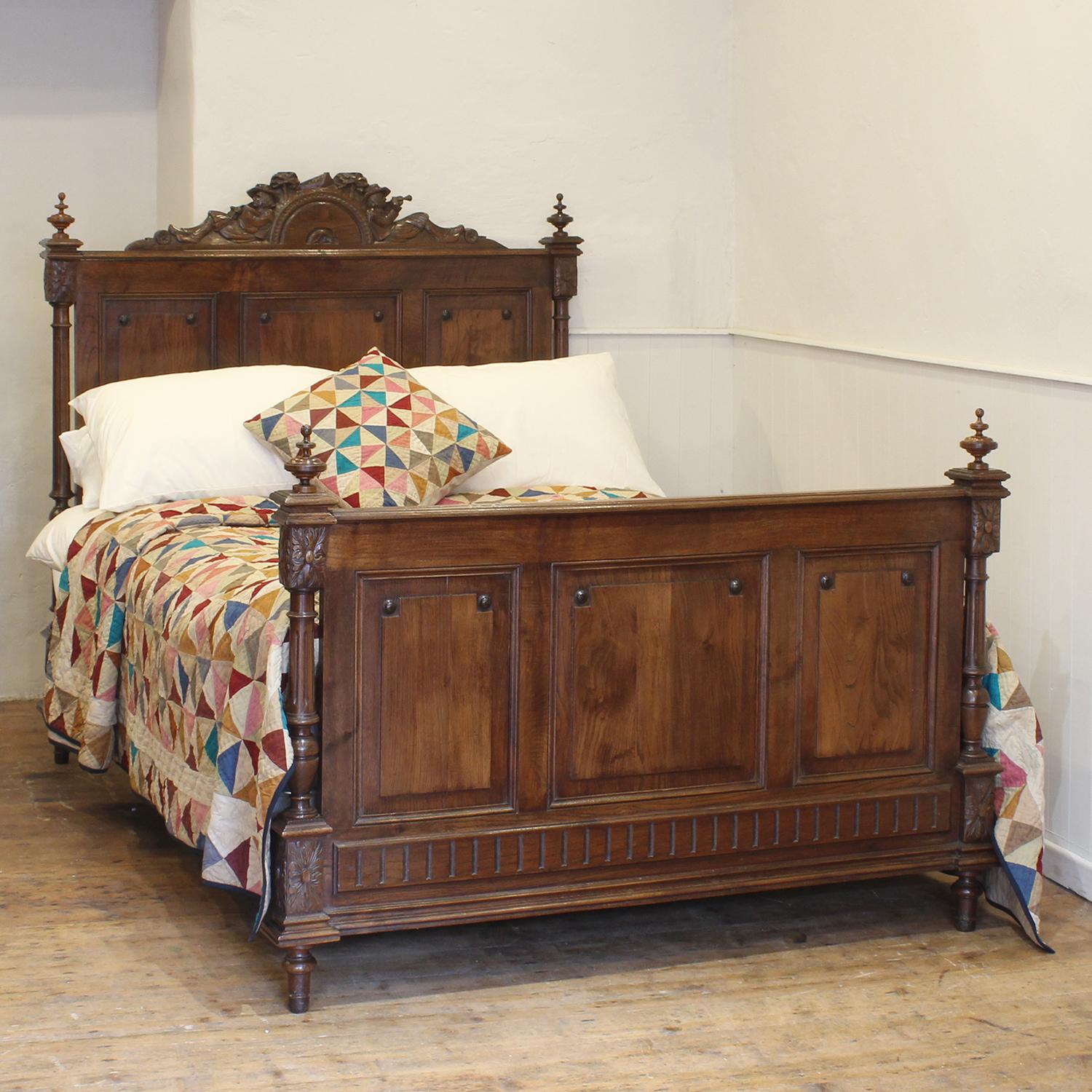 A handsome Breton bed in oak with turned posts and finials, three panel design in head and foot, and ornately carved pediment depicting a rural scene of two reclining musicians.

This bed accepts a standard double, 4ft 6in (54 in), base and mattress