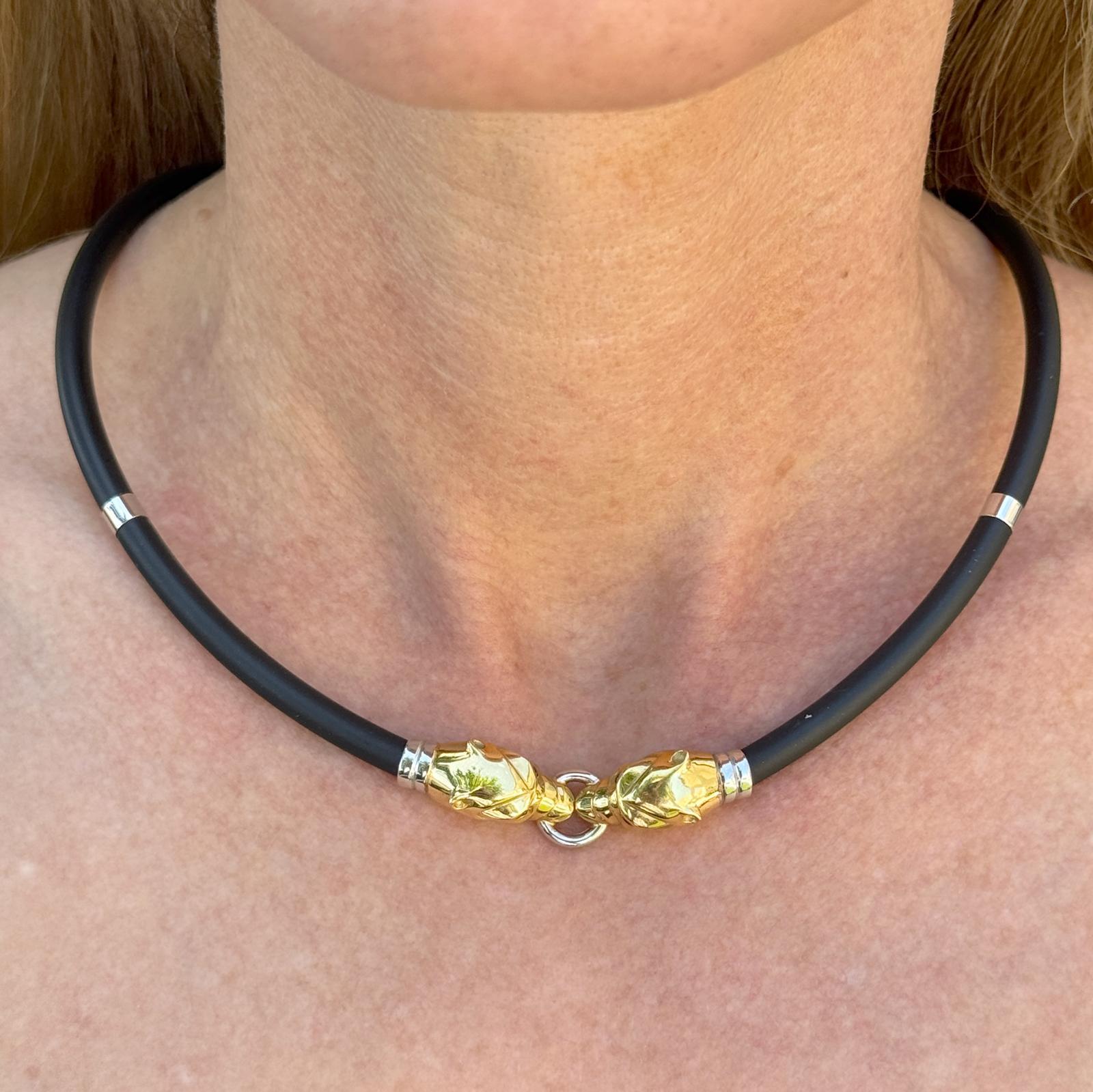 Ce collier audacieux présente deux têtes de panthère détaillées en or jaune et blanc 18 carats, reliées par un élégant cordon en caoutchouc noir pour un look contemporain et saisissant. Le contraste entre l'or chaud et le caoutchouc mat ajoute une