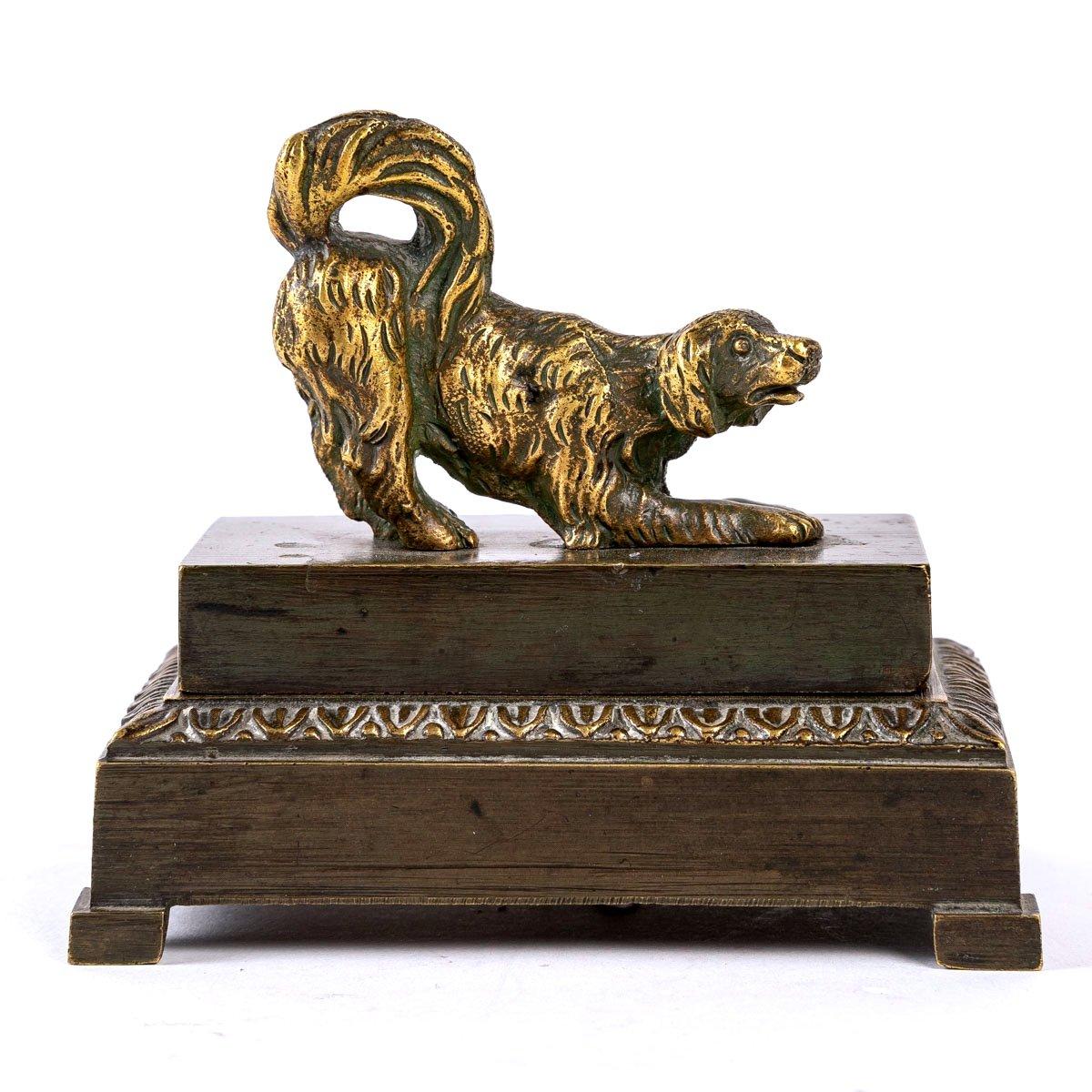 A lovely bronze inkwell, double patina, brown and gold, featuring a dog with a lively look, wanting to play, on a base with a doucine decorated with a frieze of water leaves.

This small inkwell reveals a receptacle with an inkwell, two pen