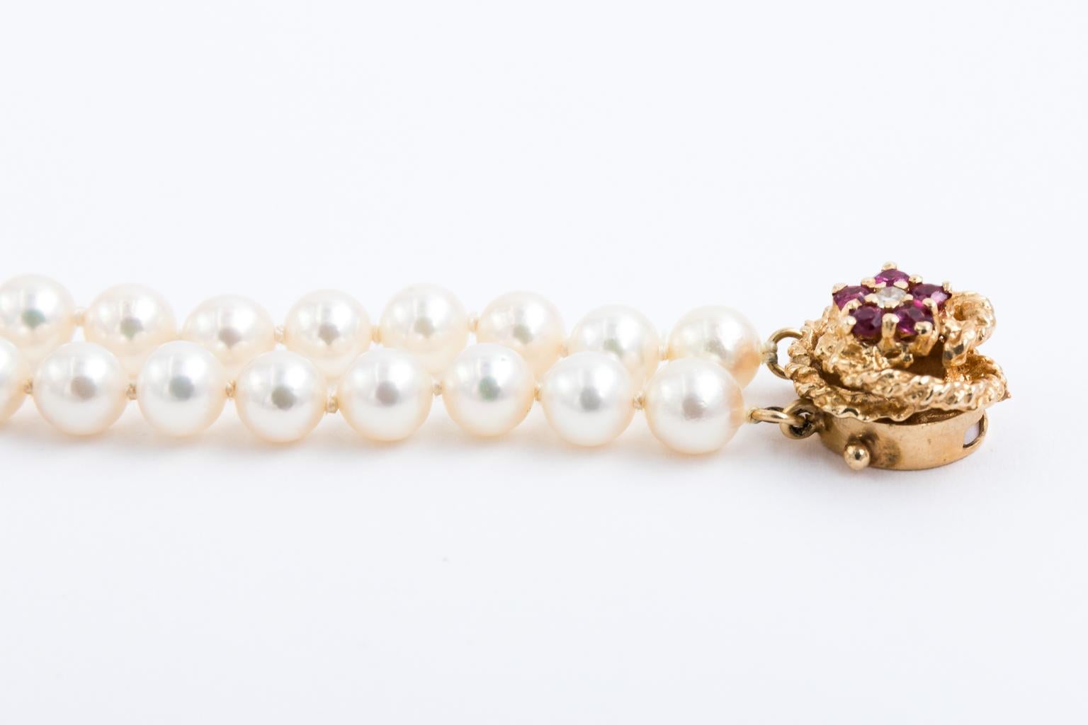 Circa 1960s double strand of 5-5.50 Millimeter Japanese cultured pearl necklace with 14 karat ruby and diamond clasp. The necklace consists of 135 pearls and 15 Inches long. The bracelet has 58 pearls and is seven inches long. The clasp also