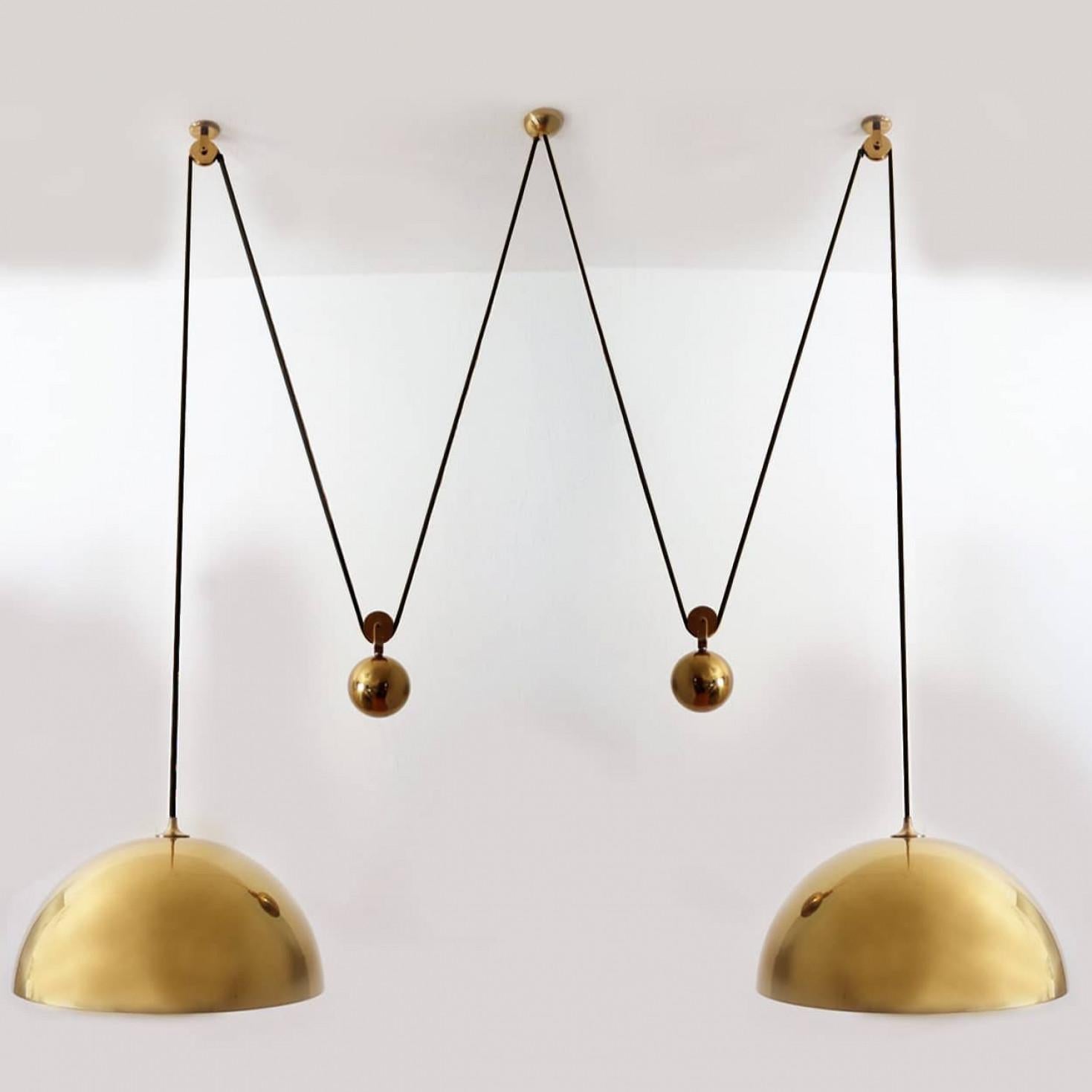 Fantástica lámpara colgante Double Pull de Florian Schulz, Alemania, Europa. Periodo de diseño: 1970-1979, periodo de producción: 2022.

Dos colgantes de latón pulido sin lacar suspendidos con su propio contrapeso de bolas de latón. Un dosel soporta
