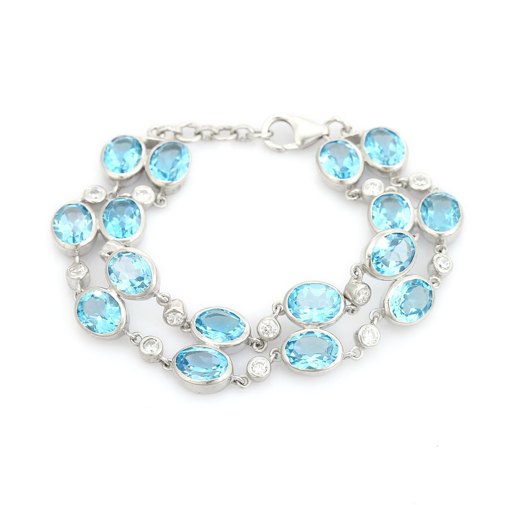 Esta pulsera de boda de doble hilera de topacio azul y circonitas es una llamativa pulsera de tenis de doble hilera elaborada en luminosa plata de ley 925. Con una exquisita disposición de gemas de topacio azul celeste de talla oval intercaladas con