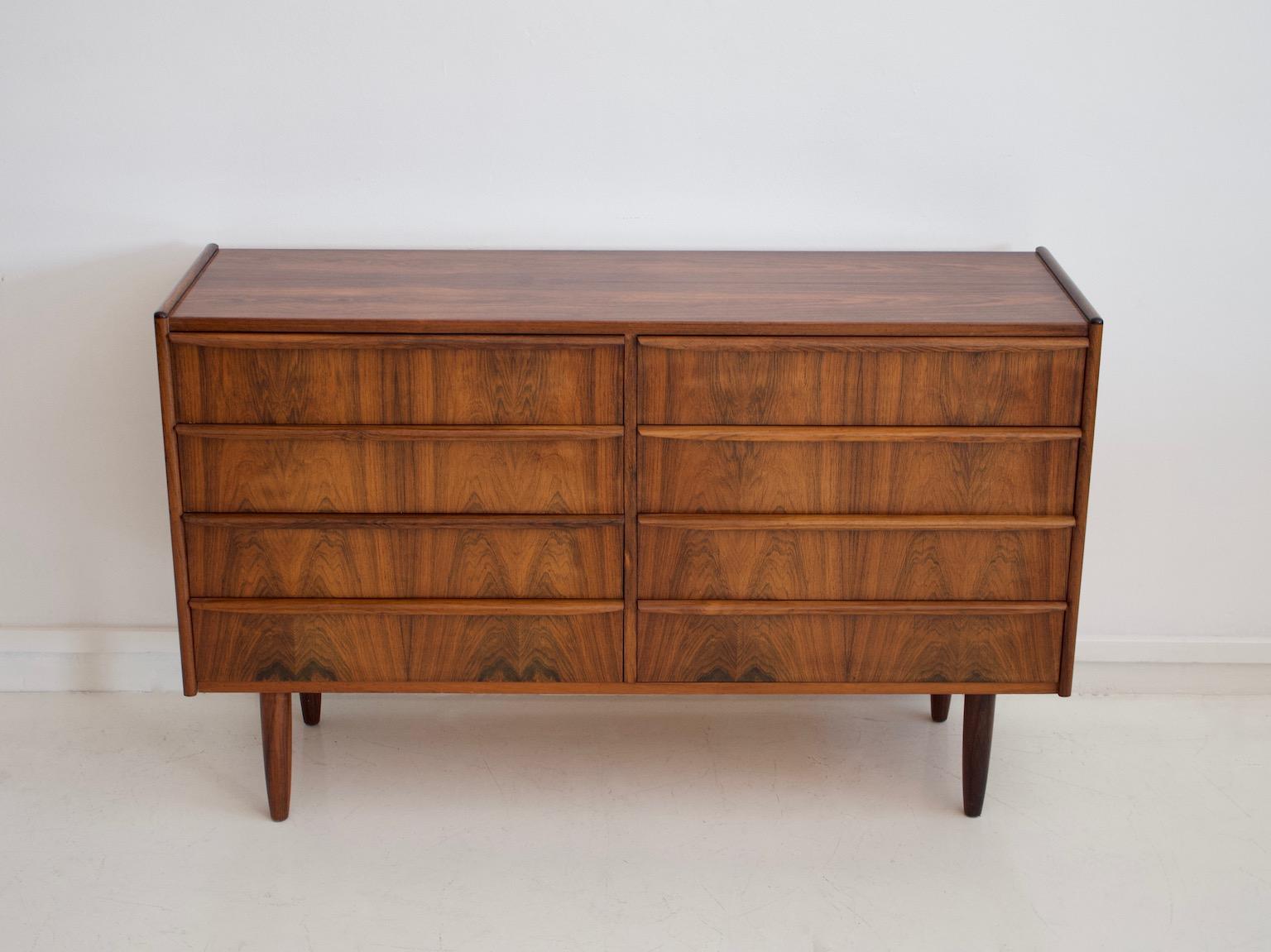 Chest made of solid rosewood and veneer with eight drawers, four on each side. Round stained wood feet.