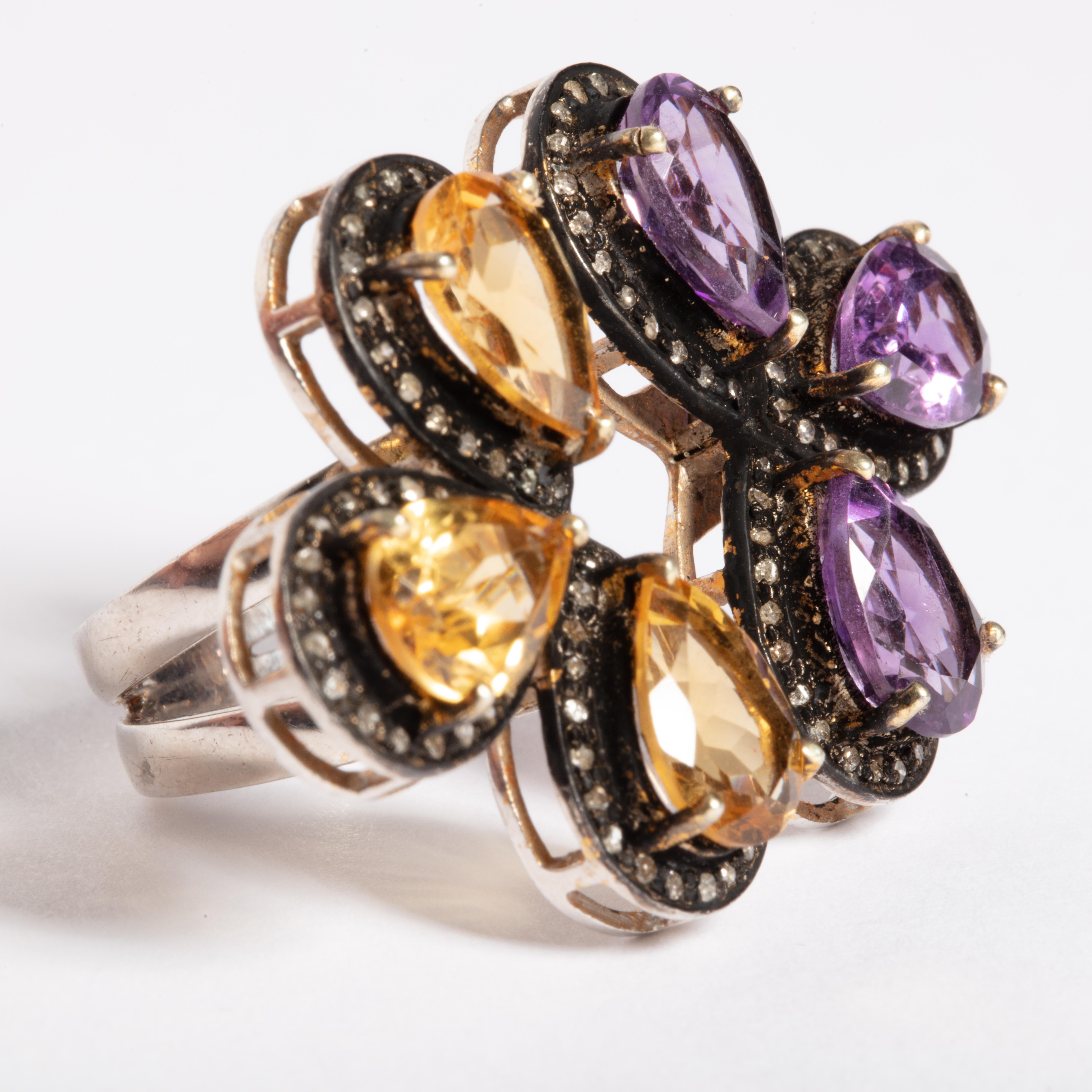 An unusual double-sided ring with faceted, pear-shaped amethyst petals on one side and faceted, pear-shaped citrines on the other bordered with pave`-set diamonds in a rhodium plate.  Band in sterling silver.  Carat weight of diamonds is .75; total