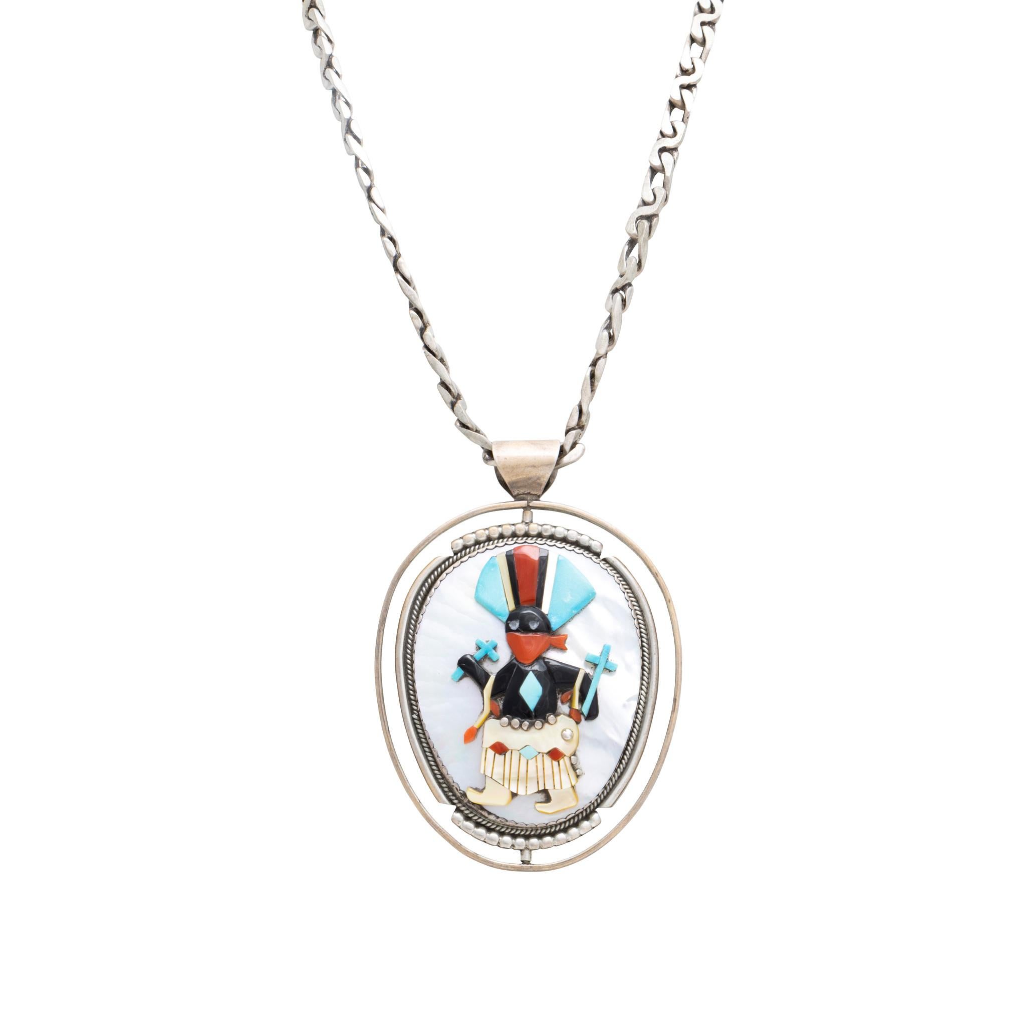 Collana con ciondolo in argento sterling e pietre multiple a doppio intarsio con kachinas. Il primo lato raffigura una kachina con testa di fango realizzata in corallo, turchese e madreperla su sfondo di onice. Il secondo lato raffigura una kachina
