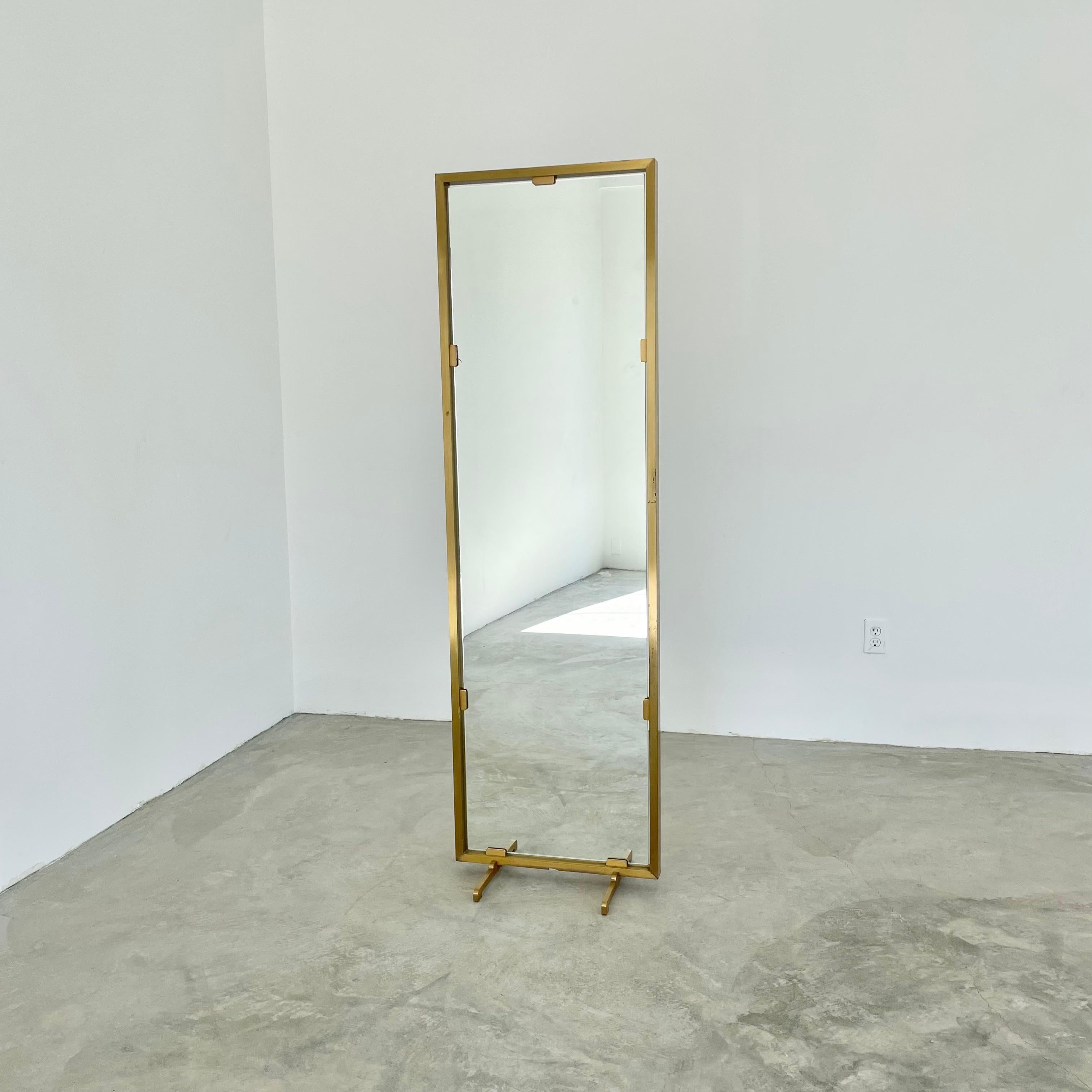 Elegant standing brass mirror. Double sided mirror stands inside the brass frame held by four brass tabs on either side. Beautiful minimalist design make this an easy piece to include in any room. Two feet at the base give perfect balance. Solid