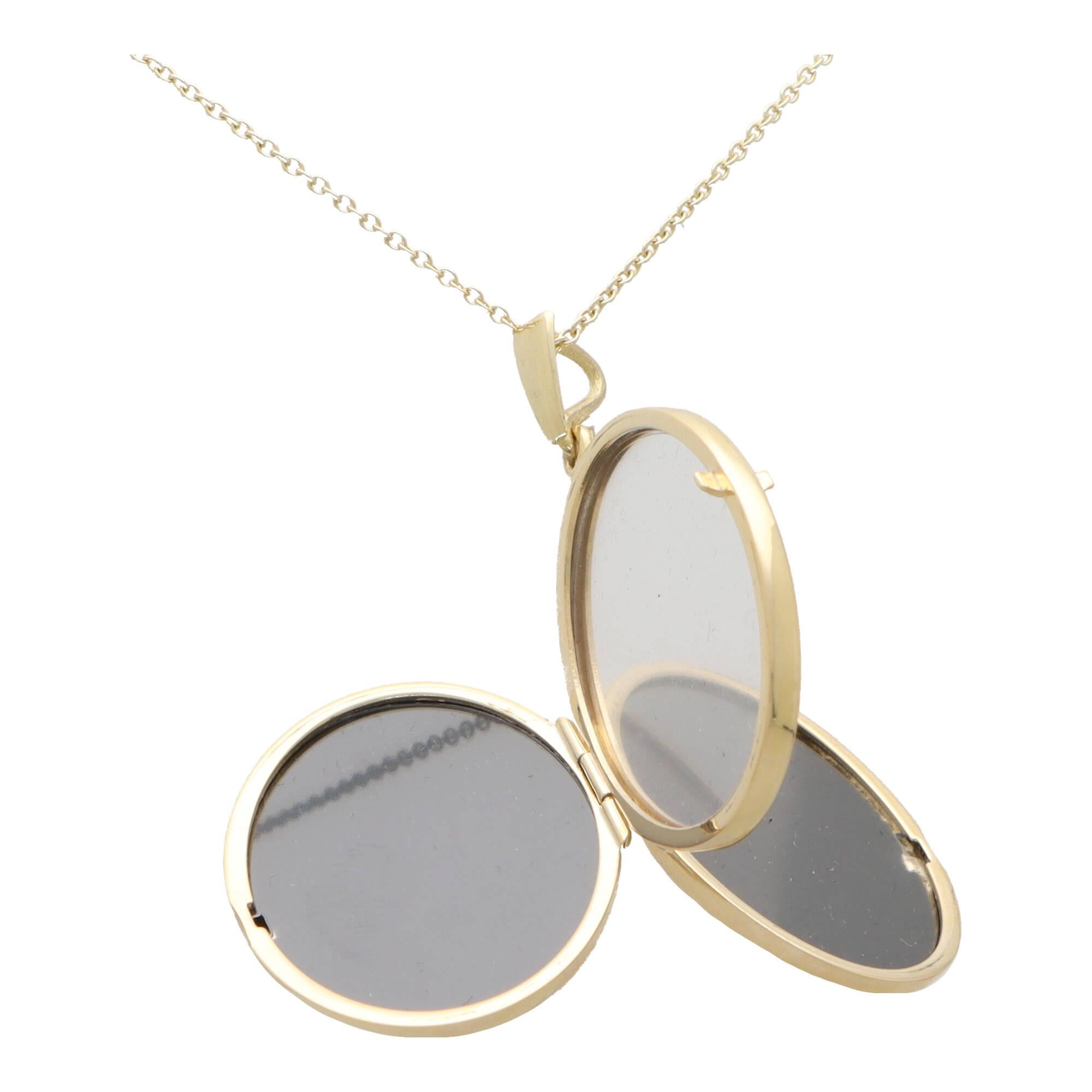 A stylish locket pendant set in 9k yellow gold.

The piece is composed of large oval shaped locket which has been left polished yellow gold so that the owner can engrave to their choosing. The locket opens from each side with the central panel being