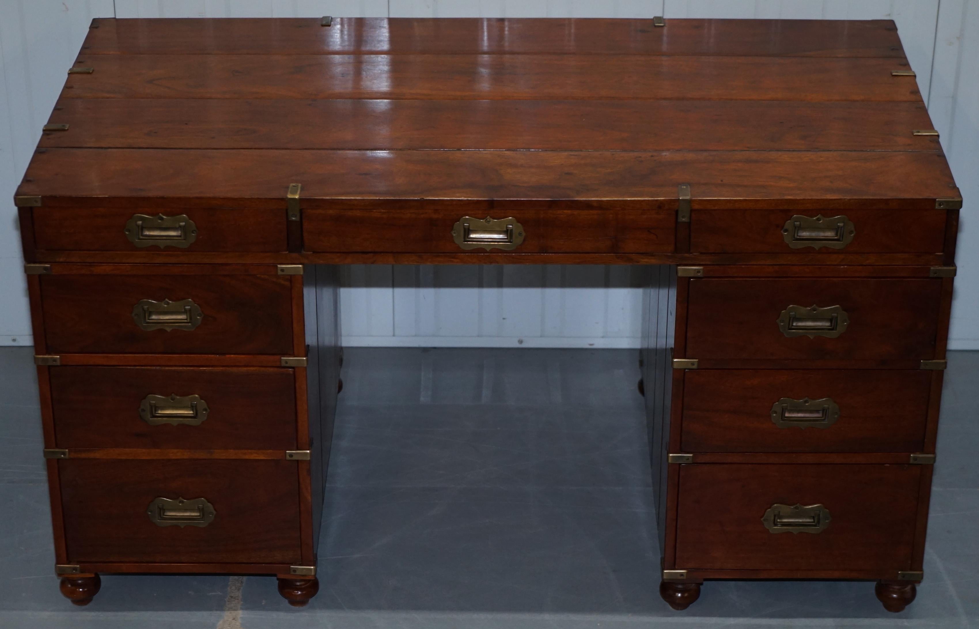 We are delighted to offer for sale this lovely very solid teak and brass military Campaign style partners desk

A good looking and well made piece, the timber patina is glorious, the desk has 9 drawers on one side and 9 false drawers on the other