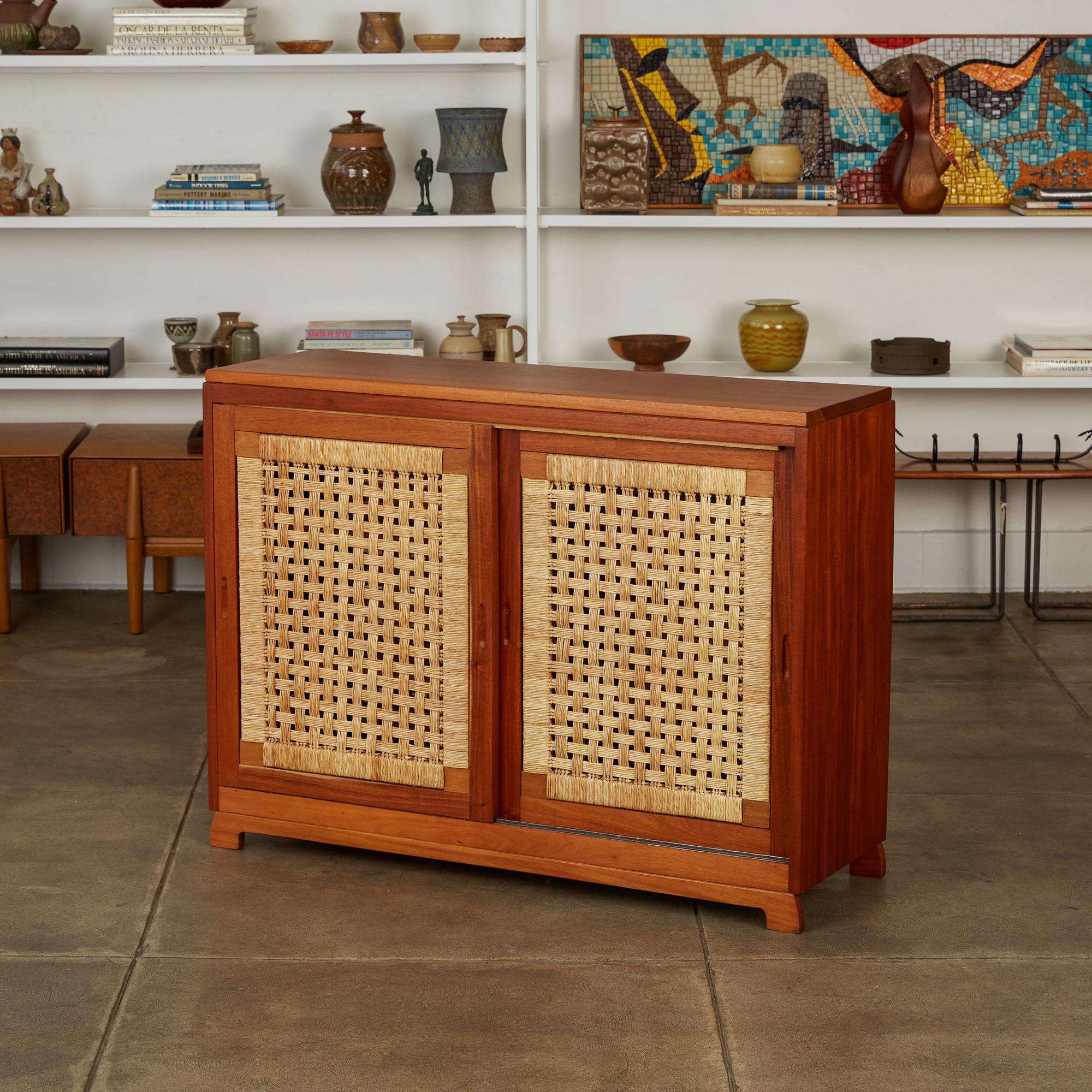 Bauhaus-trained, Mexico City-based Michael van Beuren created highly functional modern design inspired by Mexican vernacular styles and materials. This example is a compact solid mahogany credenza with double sliding doors on either side. The four