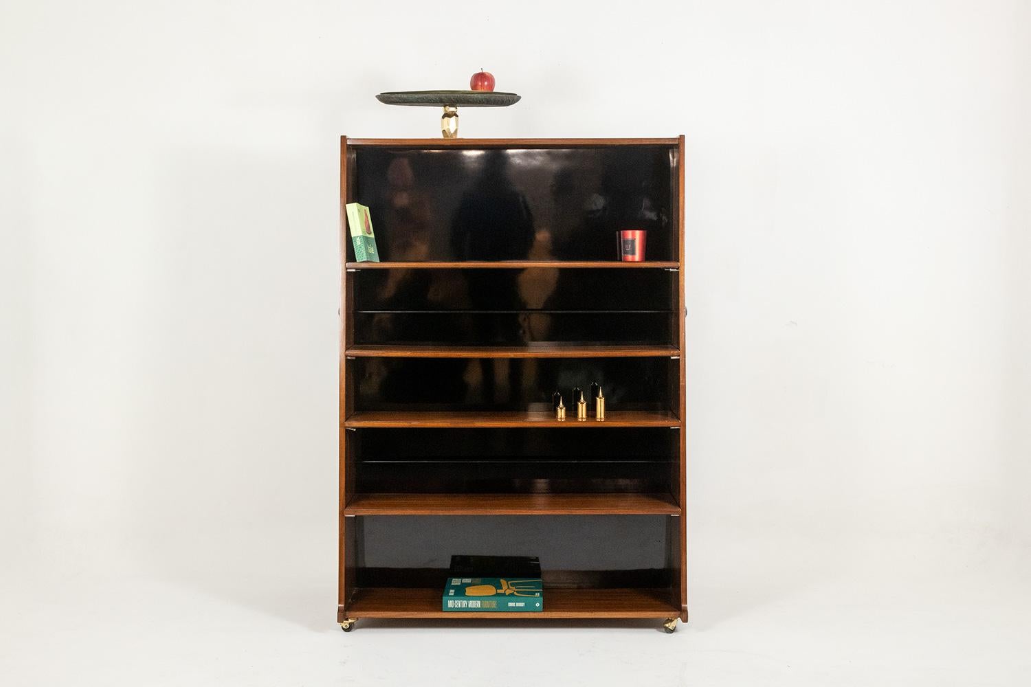 “Double-sided” bookcase in rosewood, with its black laminate bottom, presenting 5 shelves per front and ending in small casters. On the side faces, decorative fixings in a round shape.

Italian work realized circa 1960.

Dimensions: H 144 x W 100,5