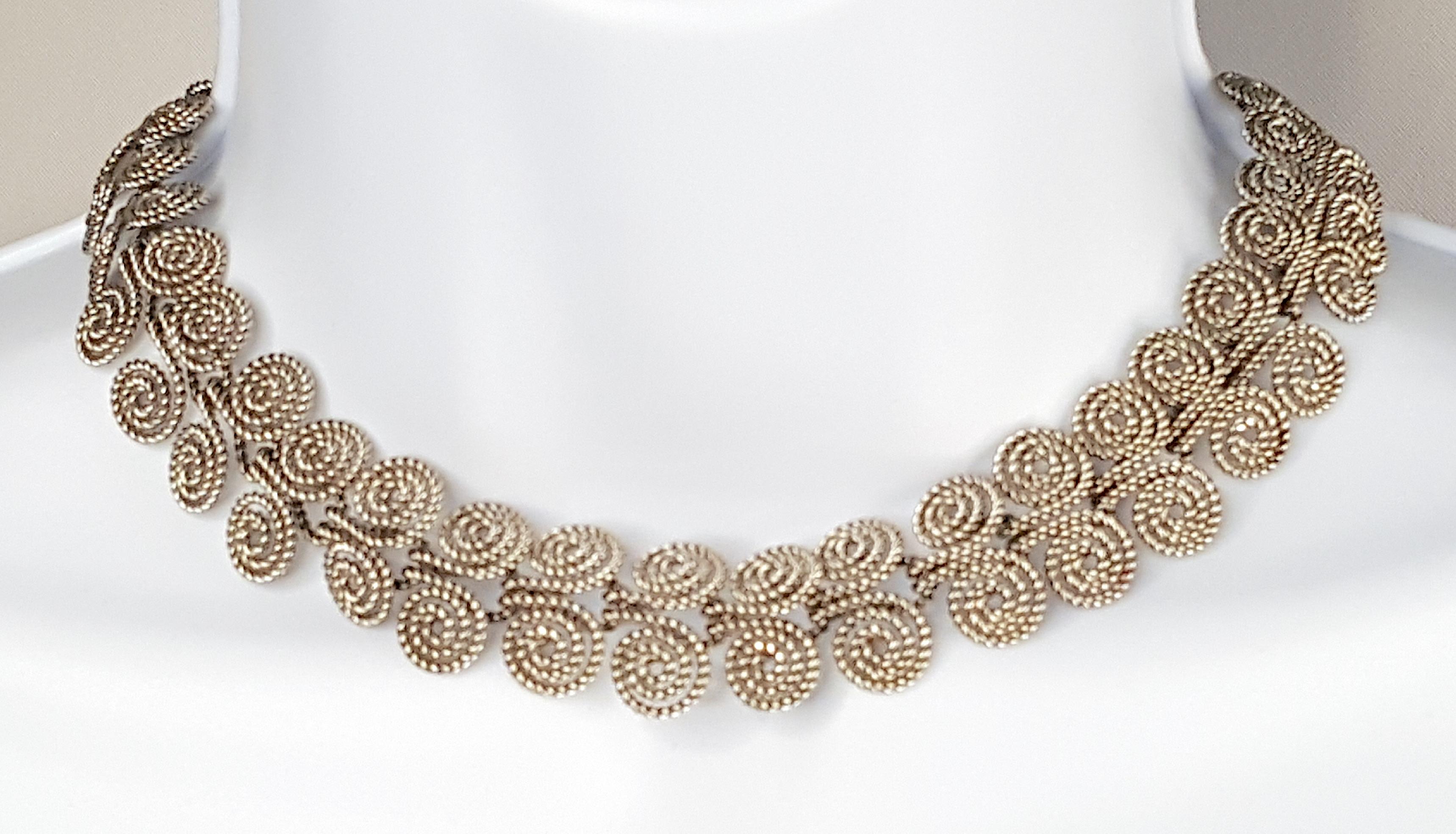 Featuring handmade double-spiral filigree links, this vintage collar choker necklace was created by tightly twisting fine silver wire, which was an artisan technique popular in the 1930s. The 34 links are virtually identical with the exception of