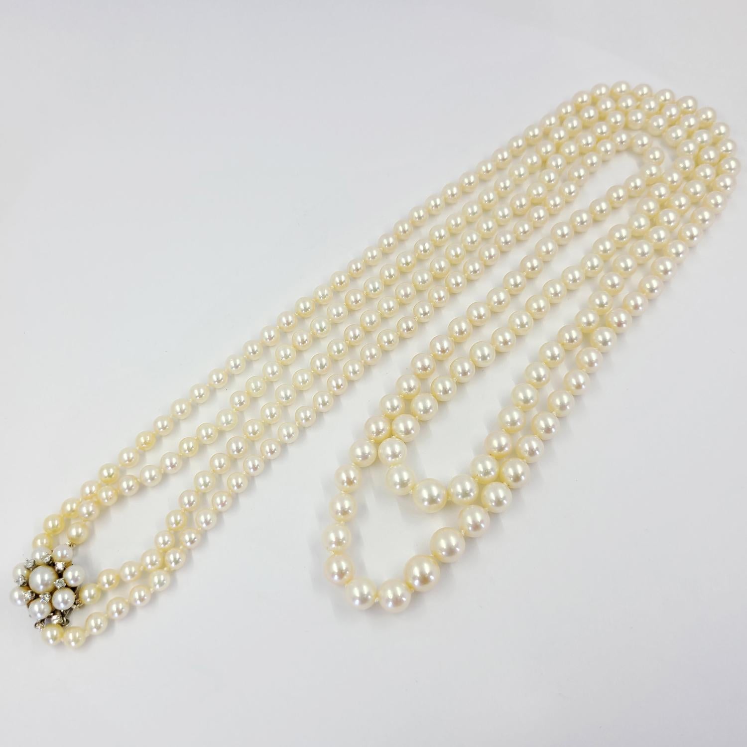 14 Karat White Gold Double Strand Cultured Pearl Necklace Measuring 32 and 34 Inches Long. 240 Round Cultured Pearls Graduate from 5mm to 8.5mm. Clasp Contains 7 Single Cut Diamonds of VS Clarity and G/H Color Total 0.15 Carats.