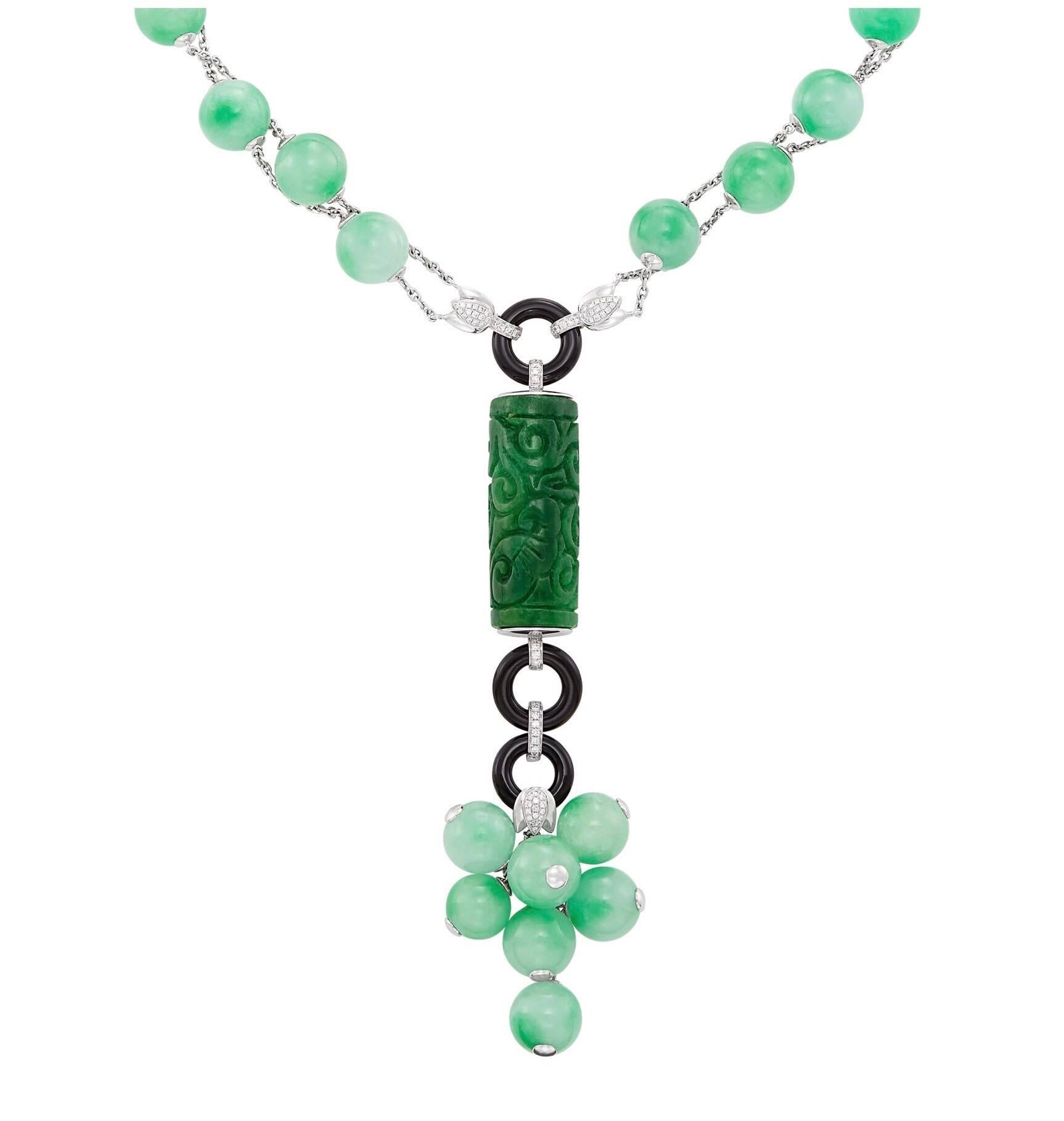 18 kt., 29 jade beads ap. 10.9 to 9.6 mm., one carved jade cylinder ap. 34.0 x 14.0 mm., small round diamonds. 

Length 17 1/2 inches. 

Jade beads: mottled light green and bright medium apple green, translucent, very good luster. 

Carved jade: