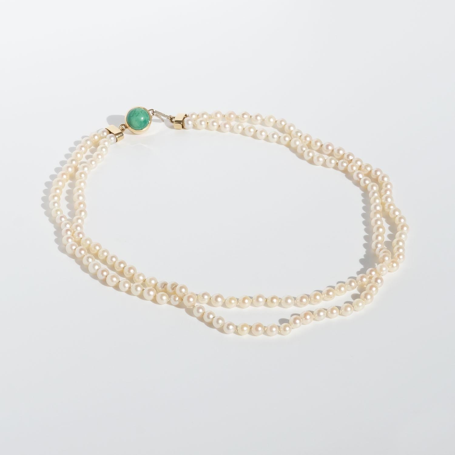 This double strand pearl necklace has cultured pearls with a beautiful creamy color. The necklace closes with a 18 karat gold hook which fastens in a bracket decorated with a green stone.

No matter if your style skews more minimalist or if you want
