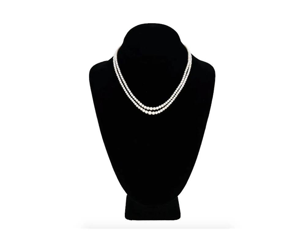 A vintage double-strand natural saltwater pearl necklace of choker length. The piece has a marquise-shaped clasp garnished with diamonds and a central faceted sapphire stone. The piece comes with The Gem and Pearl Labaratory Ltd. certificate.