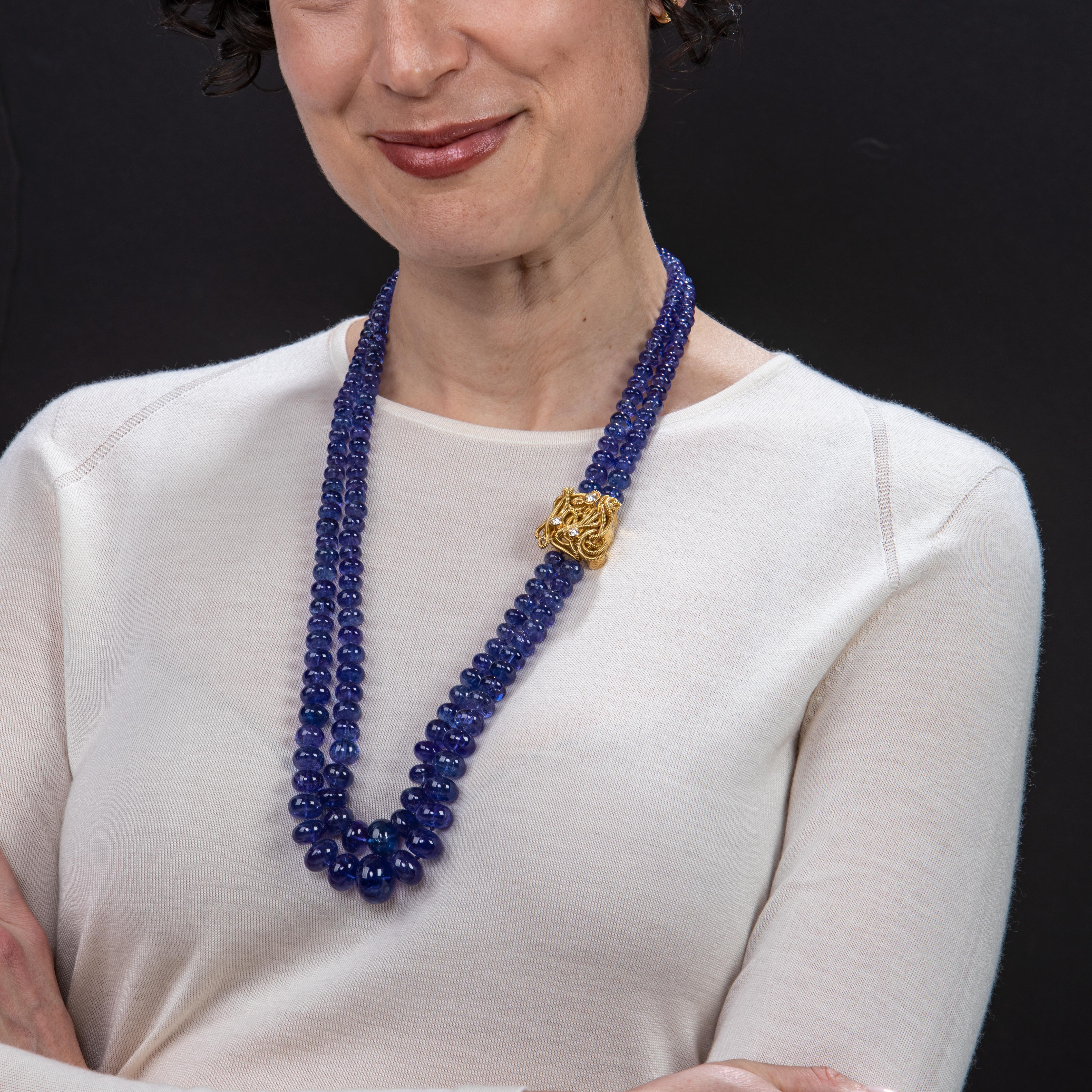 This stunning blue necklace employs a graduated double strand of tanzanite beads in various sizes, and features Gloria Bass' signature gold coil work in an 18k yellow gold clasp beset with three (3) shimmering diamonds for added elegance and