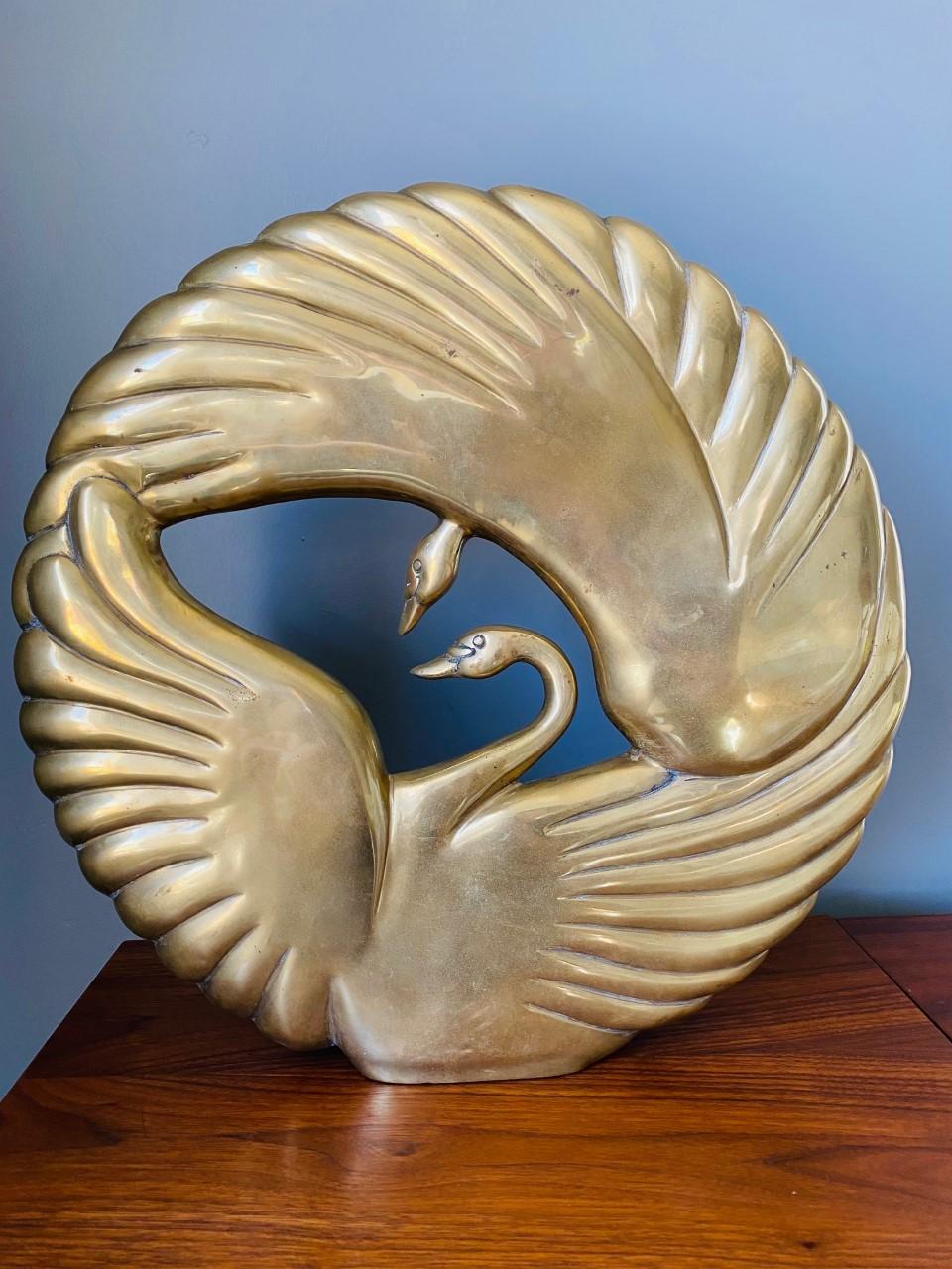 Incredibly beautiful art deco style sculpture with two swans interlocking in a circle.  This piece is attributed to Dolbi Cashier and is impactful, glamourous and chic.  The piece presents itself in a substantial size and the round shape brings