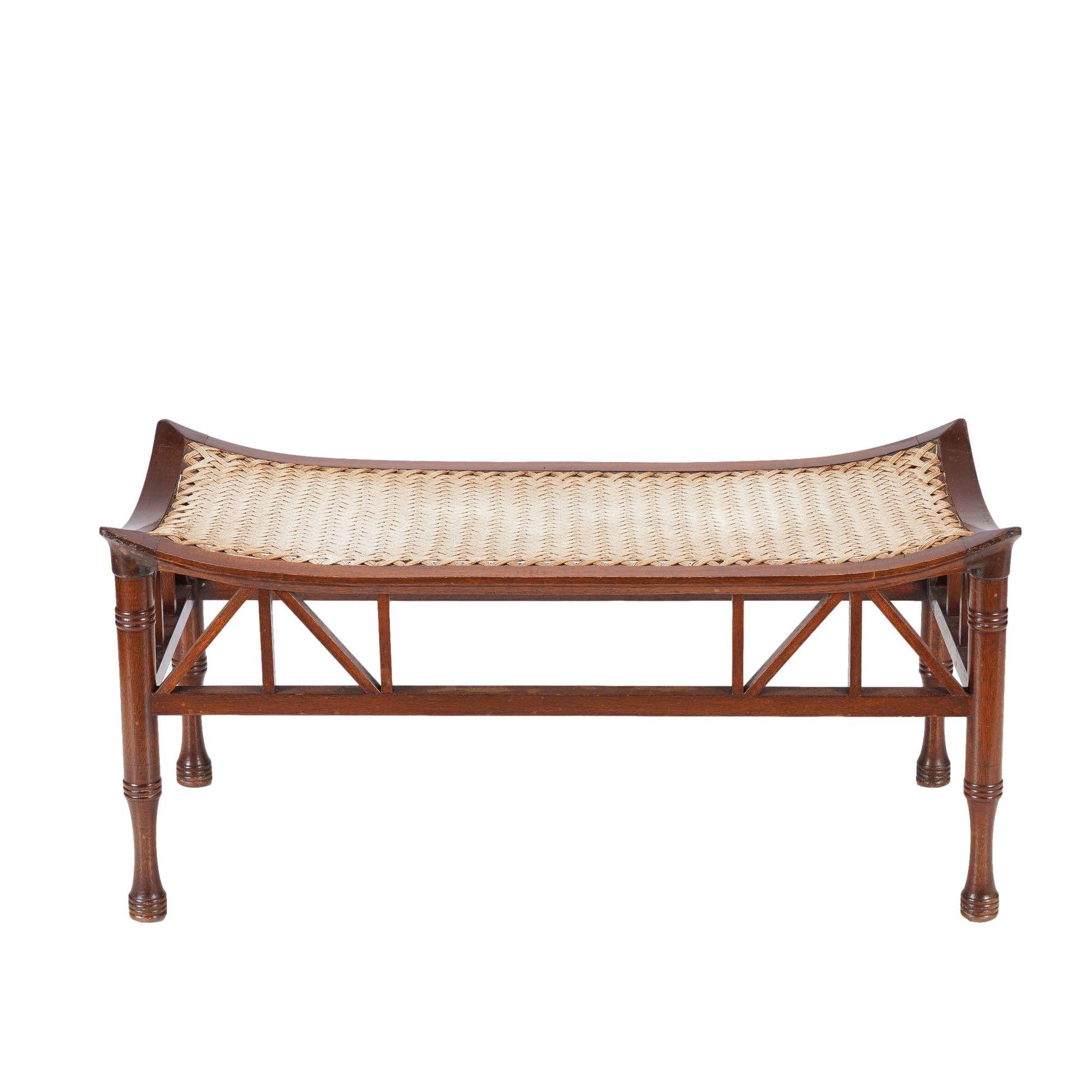 Raro taburete/banco doble Tebas fabricado para Liberty of London. El armazón del asiento, de madera dura, es abombado y está provisto del característico asiento Liberty, tejido a mano con cuatro cordones de lino, sobre patas torneadas y perfiladas