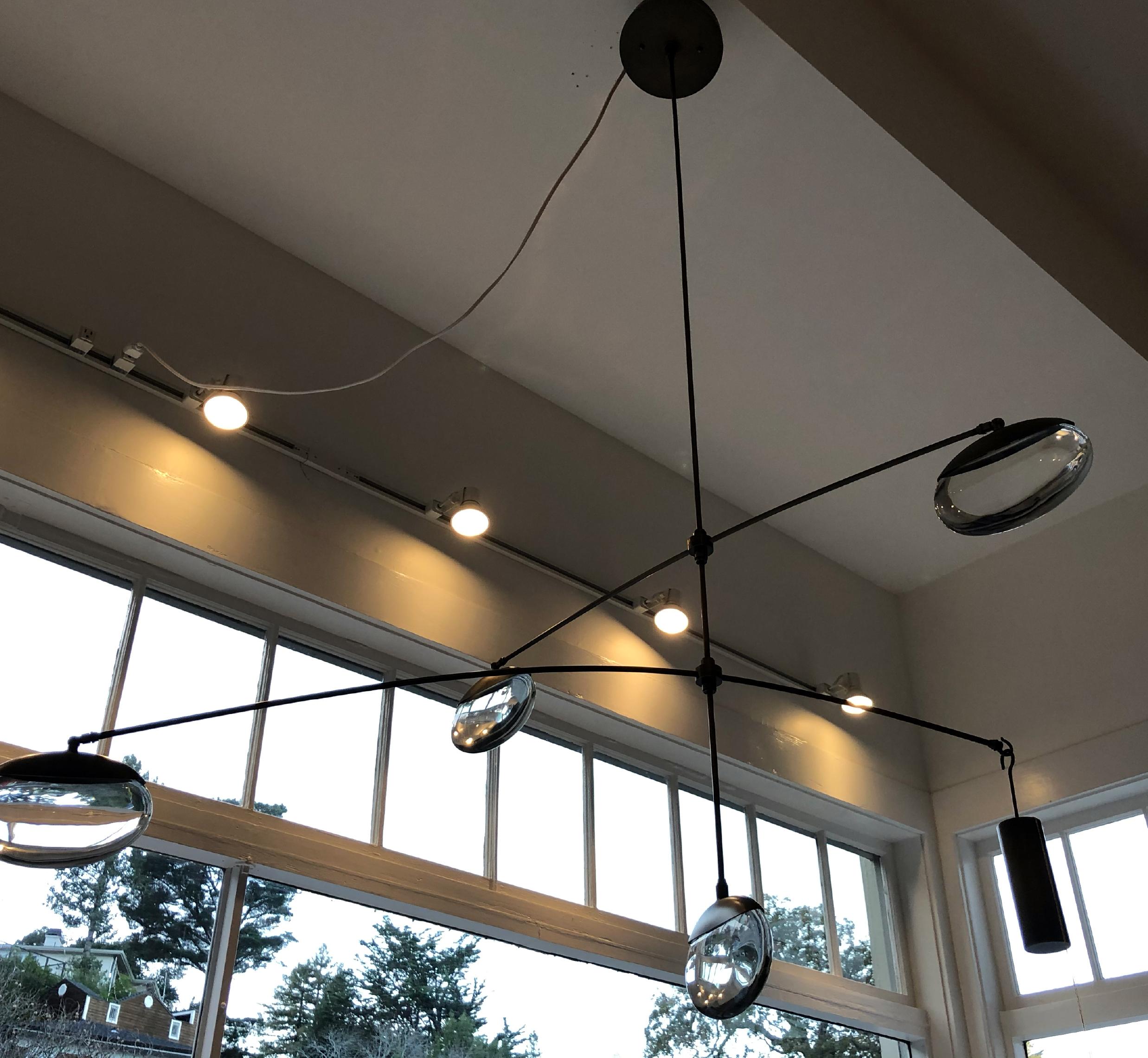 Double-tiered chandelier with four hand blown elliptical spheres and an articulated bronze armature with a bronze counterweight and matching canopy.