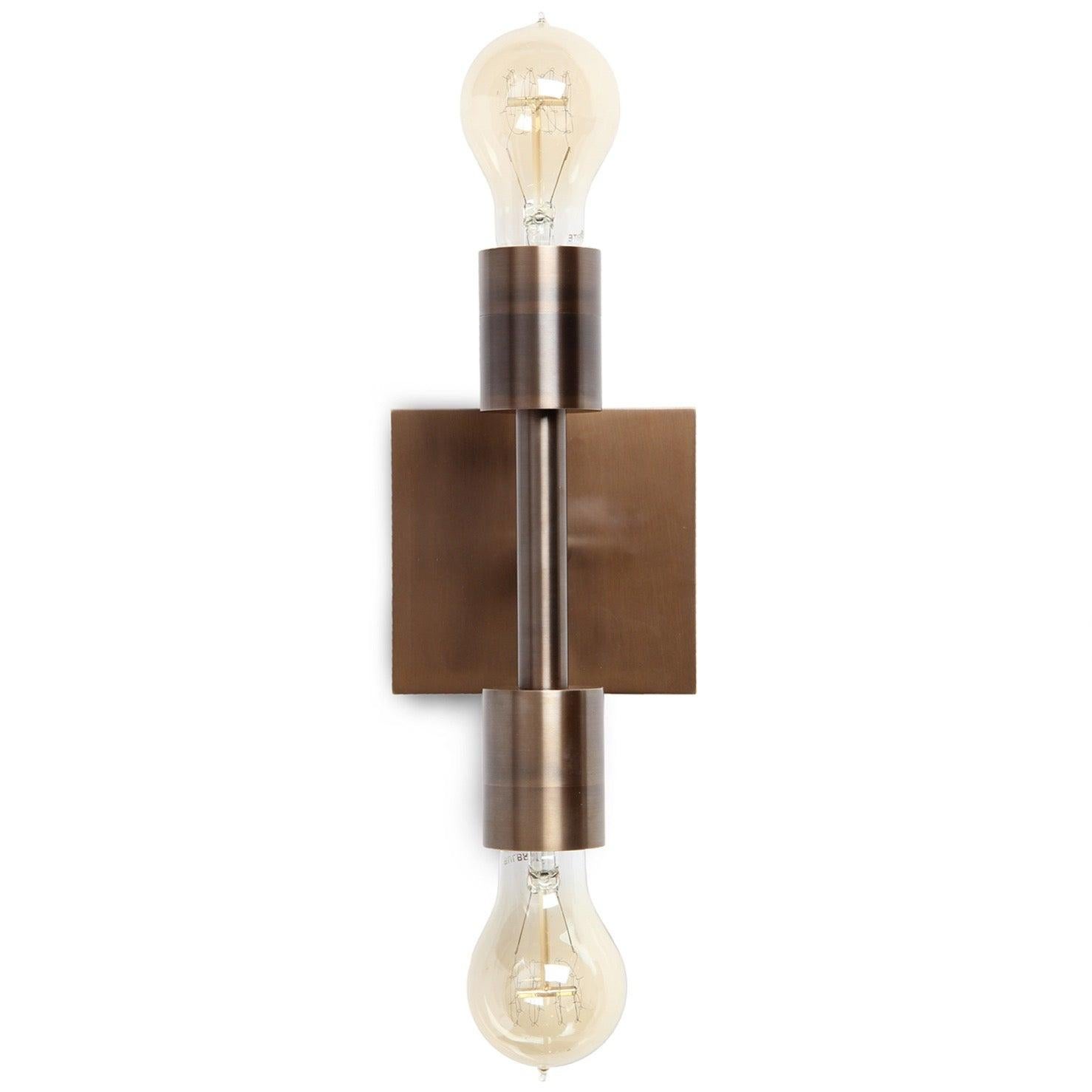 Una doppia applique da parete realizzata in studio con una forma architettonica essenziale, realizzata in ottone massiccio. Disponibile nelle finiture lucida, spazzolata e patinata.