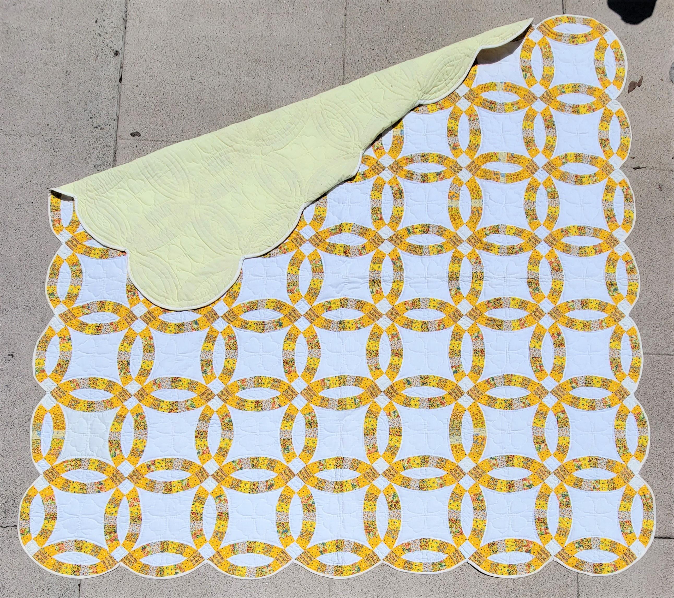 This fine 20thc yellow & white double wedding ring quilt has a Dutchy Pennsylvania calico fabric.The quilting is very good and piecework too. This is a later quilt and very big.It will fit a queen or king bed and has a scalloped border.