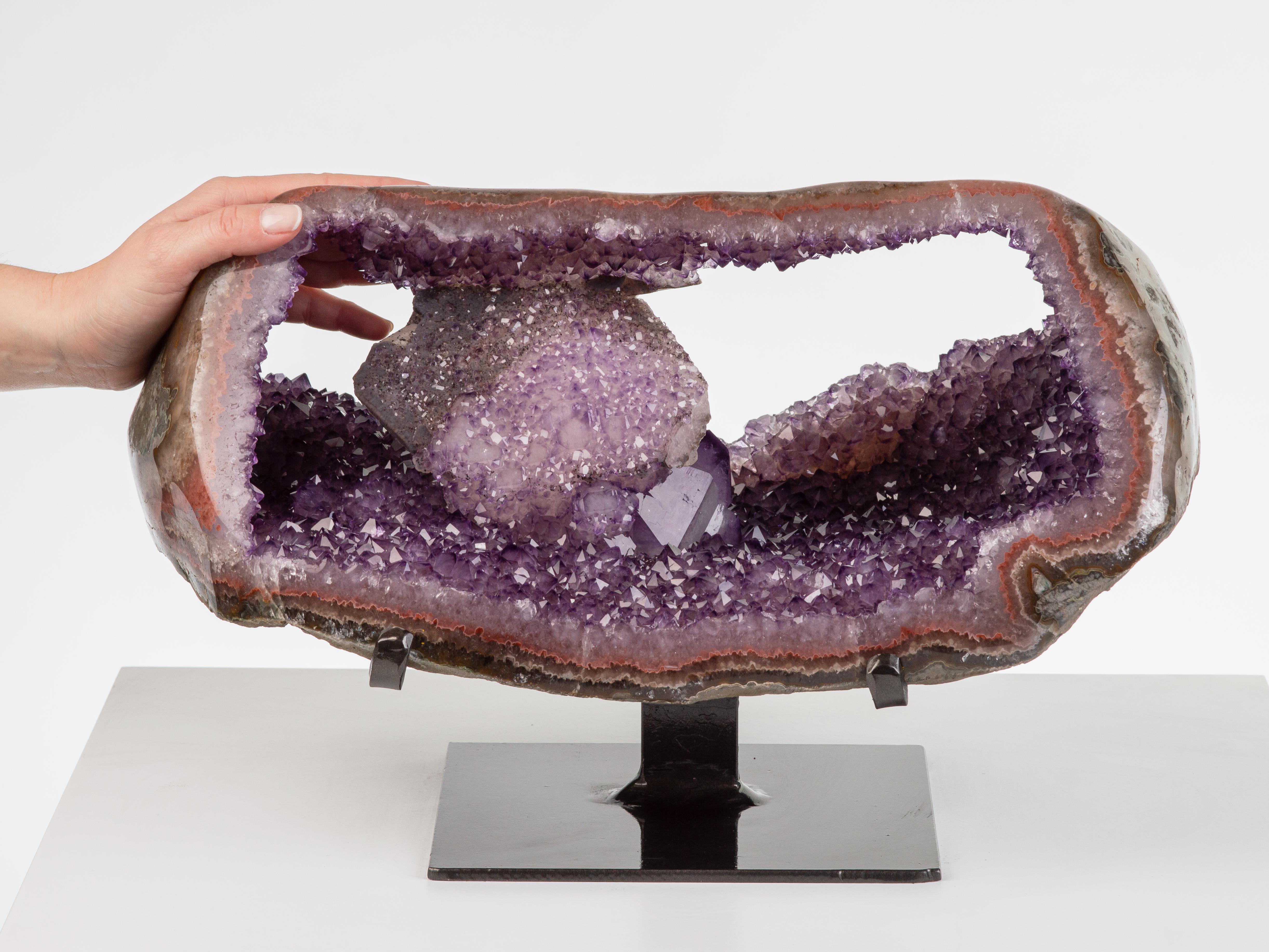 The central element of this geode has been preserved with two windows
on each side, revealing gorgeous calcite formations sat on a blanket of
differentially tinted amethystine quartz. The calcite itself is overlaid with
white quartz and blackish