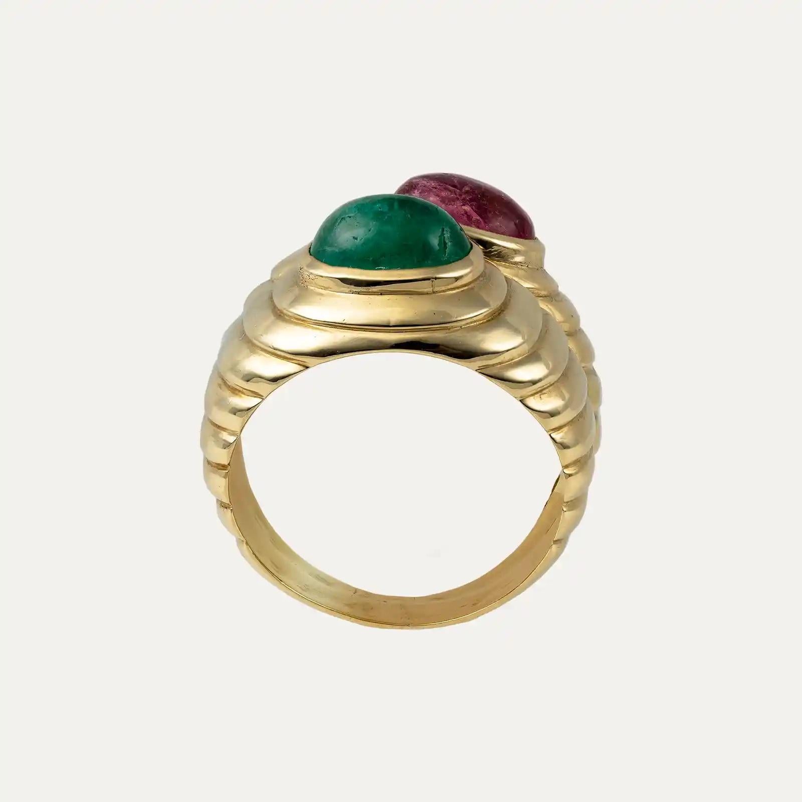 
Bague double en or jaune 14kt - 585‰, avec un design massif et structuré présentant des courbes douces et polies avec un motif ondulé. Serti de deux pierres précieuses ovales taillées en cabochon, une émeraude verte totalisant environ 1,15ct, et