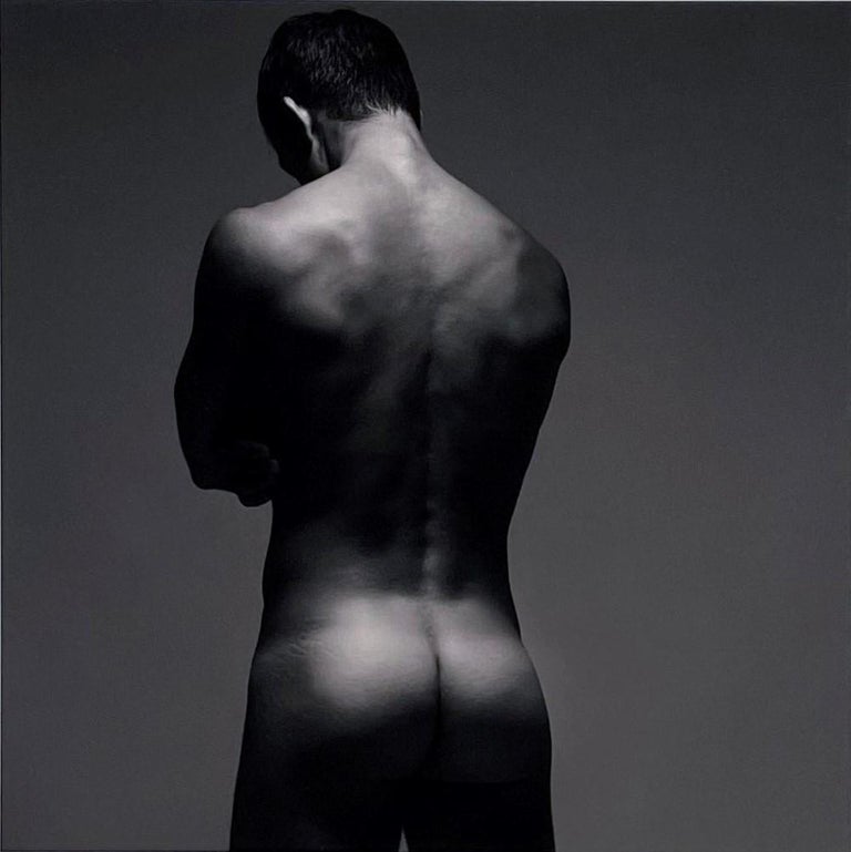 The gorgeous muscular physique of the nude male in Doug Birkenheuer's photograph titled "Backside" is highlighted with the play of light and shadows.  This sepia toned photograph captures all the defined muscles and contours of the subject.  The
