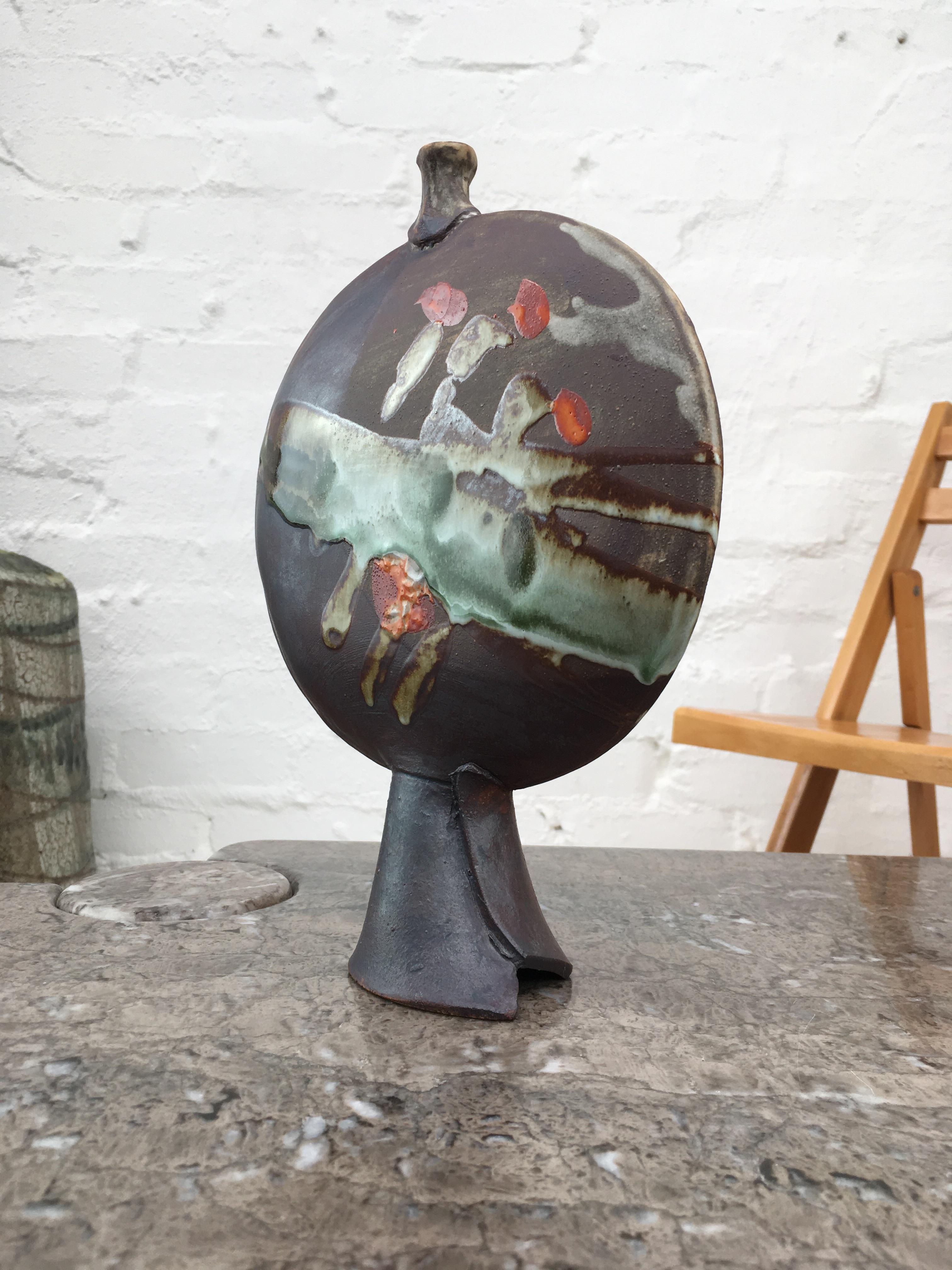 This lovely double faced vase comes from a series by Doug Lawrie. It bears his chop to the side of the base and a paper label, signed and numbered, DL 86. 

We love this vase for it's two wonderful moon-like faces and how lightly it floats on it's