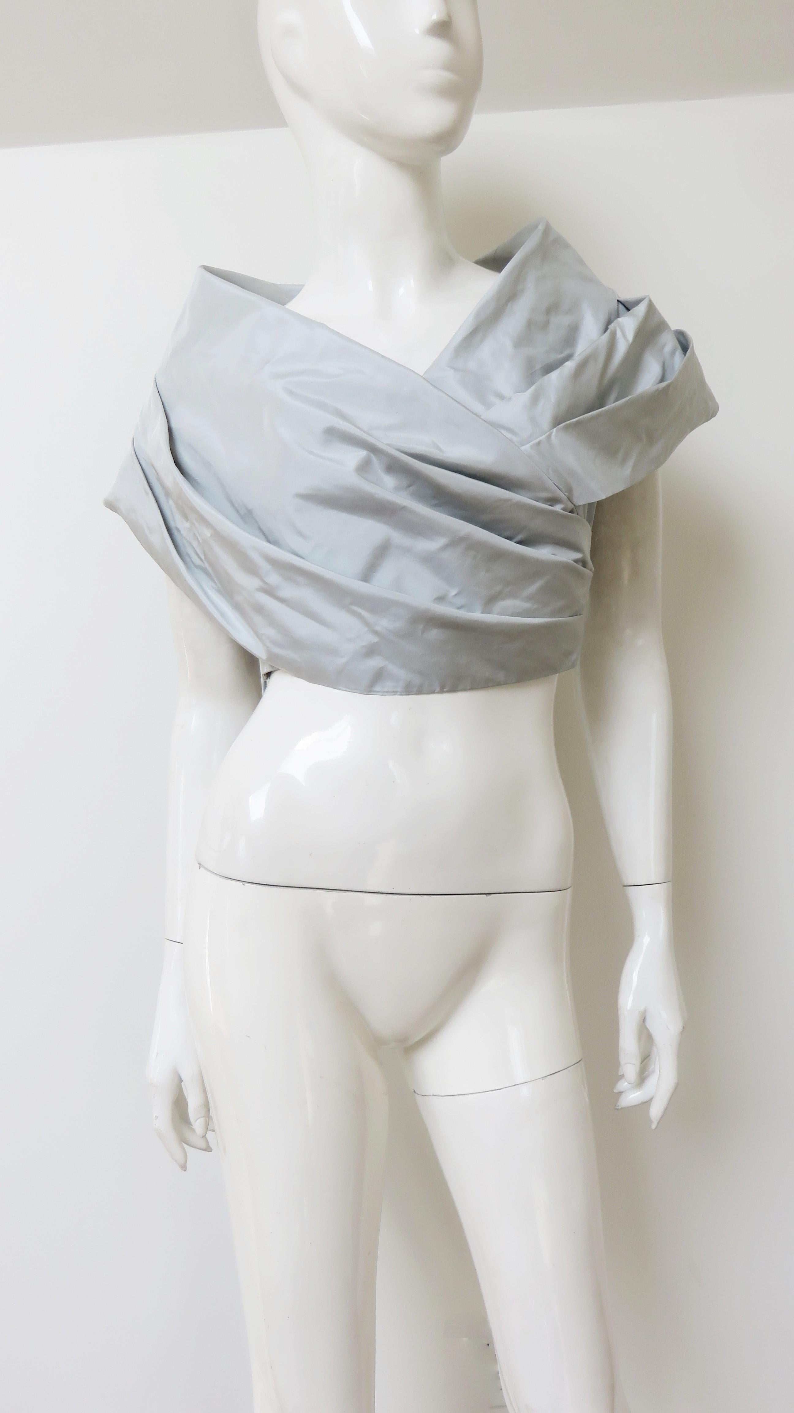 A light grey silk crop top by Douglas Anderson.  It has a draped portrait collar falling in folds across the upper arms crossing in the front.  It is lined in the same fabric and has a side zipper. New with tags.
Fits sizes Small, Medium.  Marked US