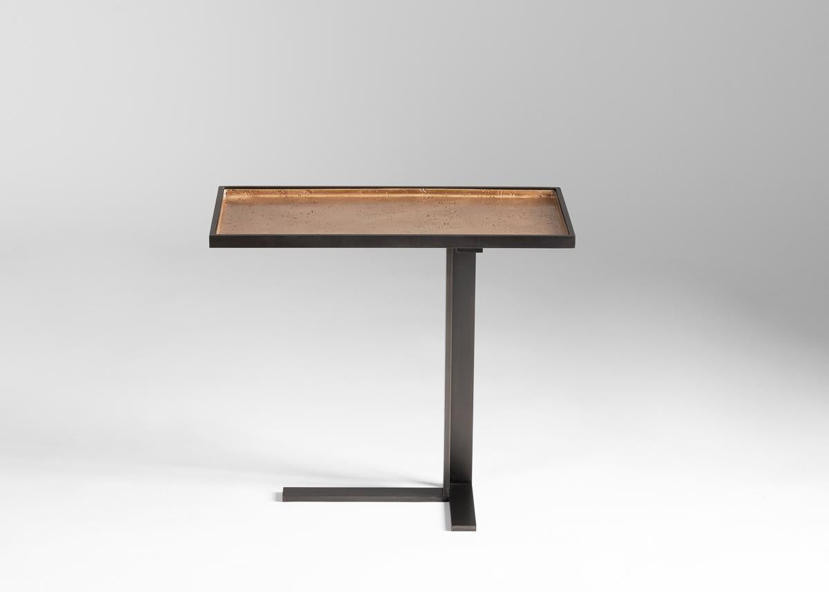 This geometric, cantilevered side table, an industrial arrangement of right angles in bronze and cold blackened steel, is adorned by a playful burnished top.

Drawing from his knowledge of art and design (in addition to his architectural