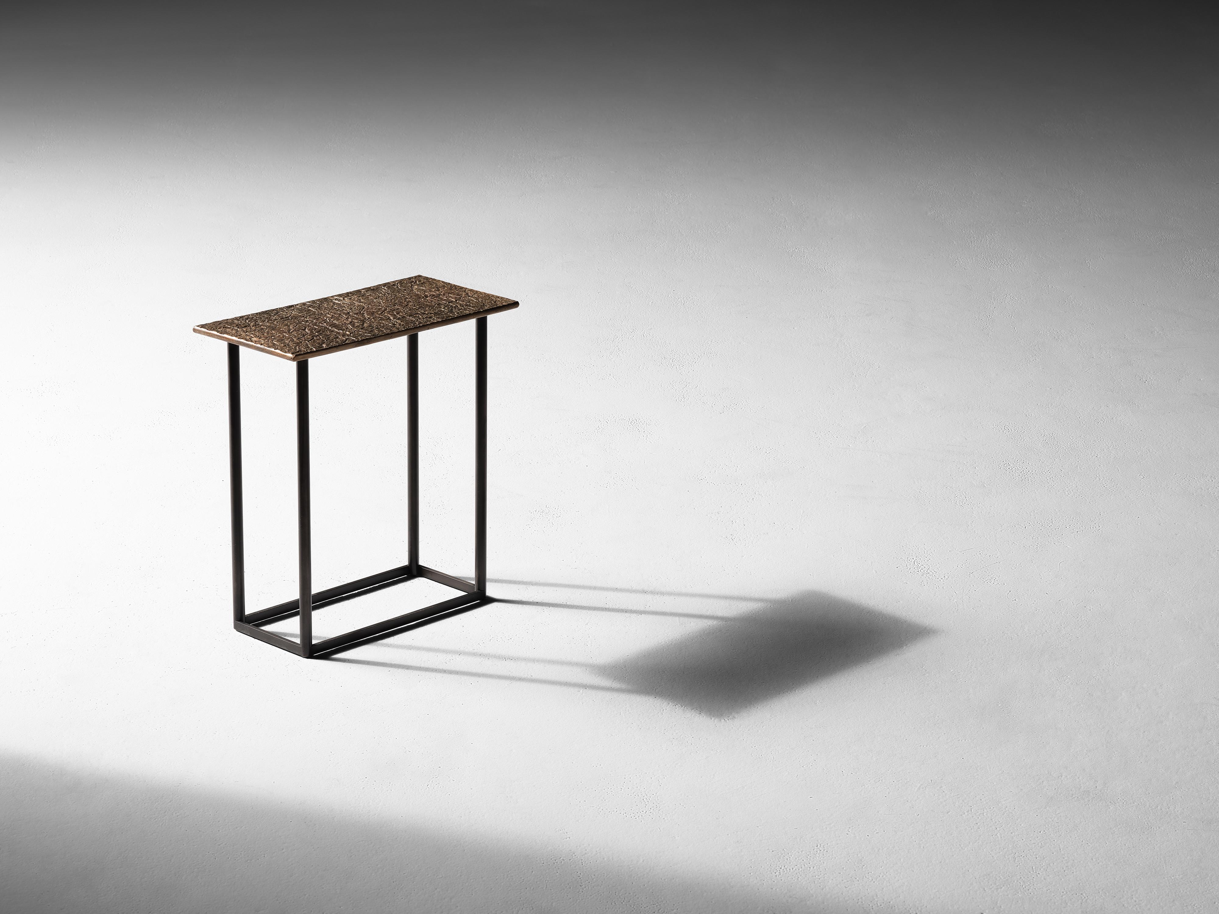 Created in collaboration with Nick Alan King.

This geometric side table, an industrial arrangement of right angles in bronze and cold blackened steel, is adorned by a playful top reminiscent of a section of parched earth.

Drawing from his