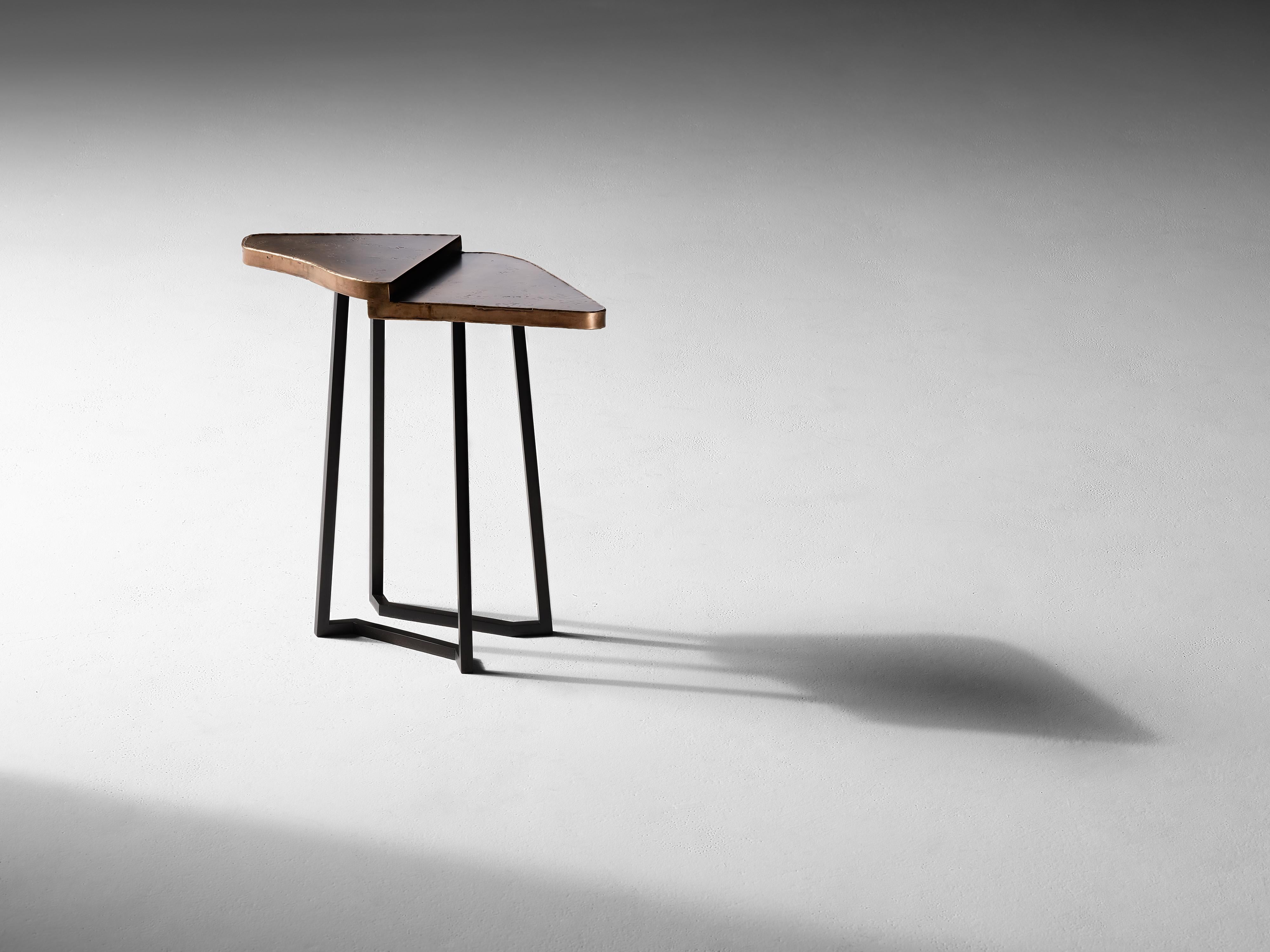 Crossover, a remarkable side table in dappled brass and blackened steel, is not just a work of supreme craftsmanship, but, with its geometric legs and unusual top (divided into two separate planes), one which achieves an elegance borne of