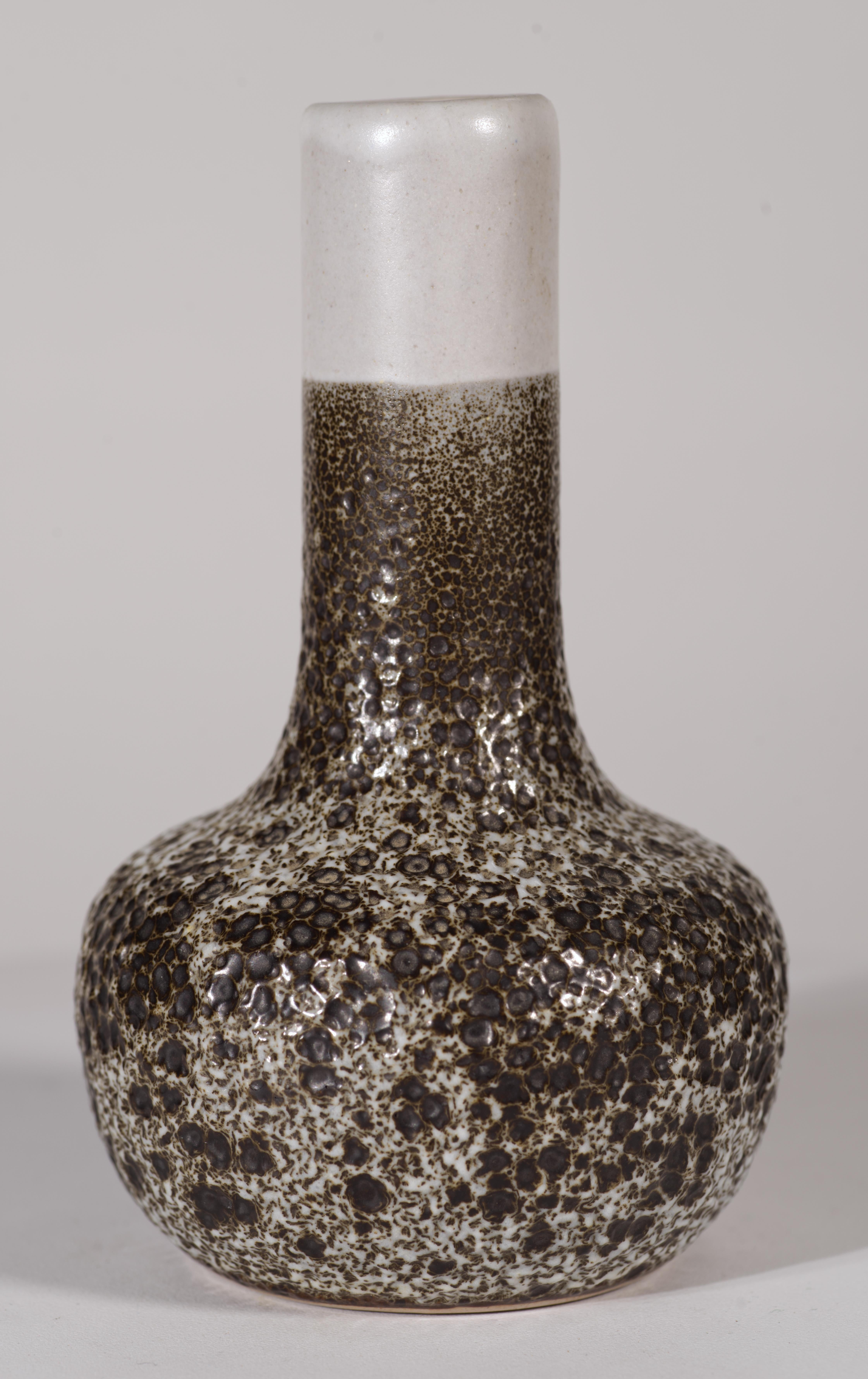  Il vaso vintage realizzato a mano presenta la complessa smaltatura Crater nei colori bianco sporco e marrone espresso. La palette di colori minimale e la forma snella del pezzo permettono allo smalto testurizzato con variazioni da semi-opaco a