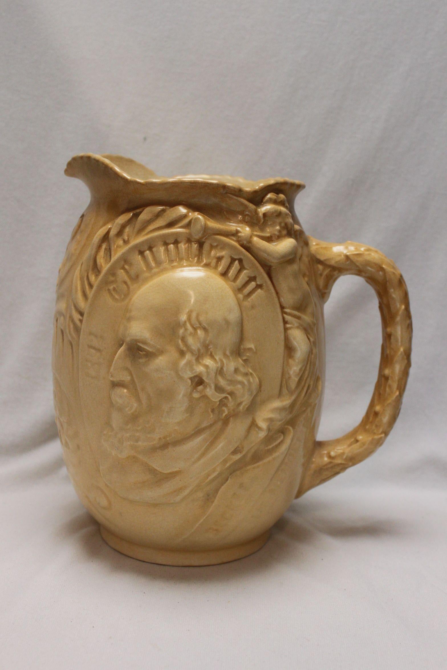 This Doulton Burslem jug was issued in 1892 to mark the death of Alfred, Lord Tennyson (1809-1892), who was the Poet Laureate from 1850 until his death. On either side of the jug are moulded semi-relief busts of Tennyson, one with a trumpet wielding