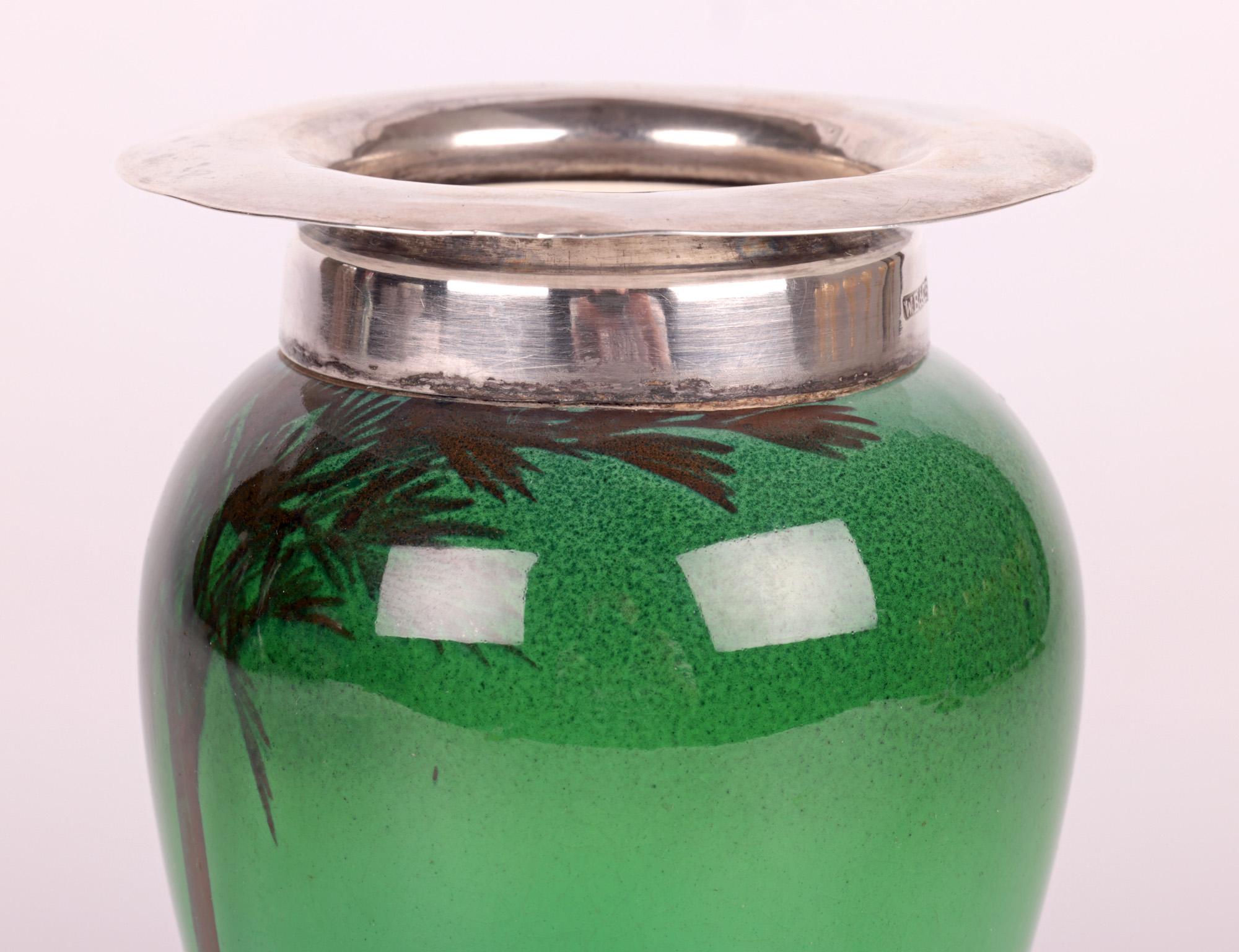 Un beau et inhabituel vase flambe vert monté en argent Doulton Burslem series ware avec une scène d'oasis dans le désert datant d'environ 1909. Le vase en céramique à pot épais repose sur un pied étroit à jupe, avec un haut corps bulbeux et un