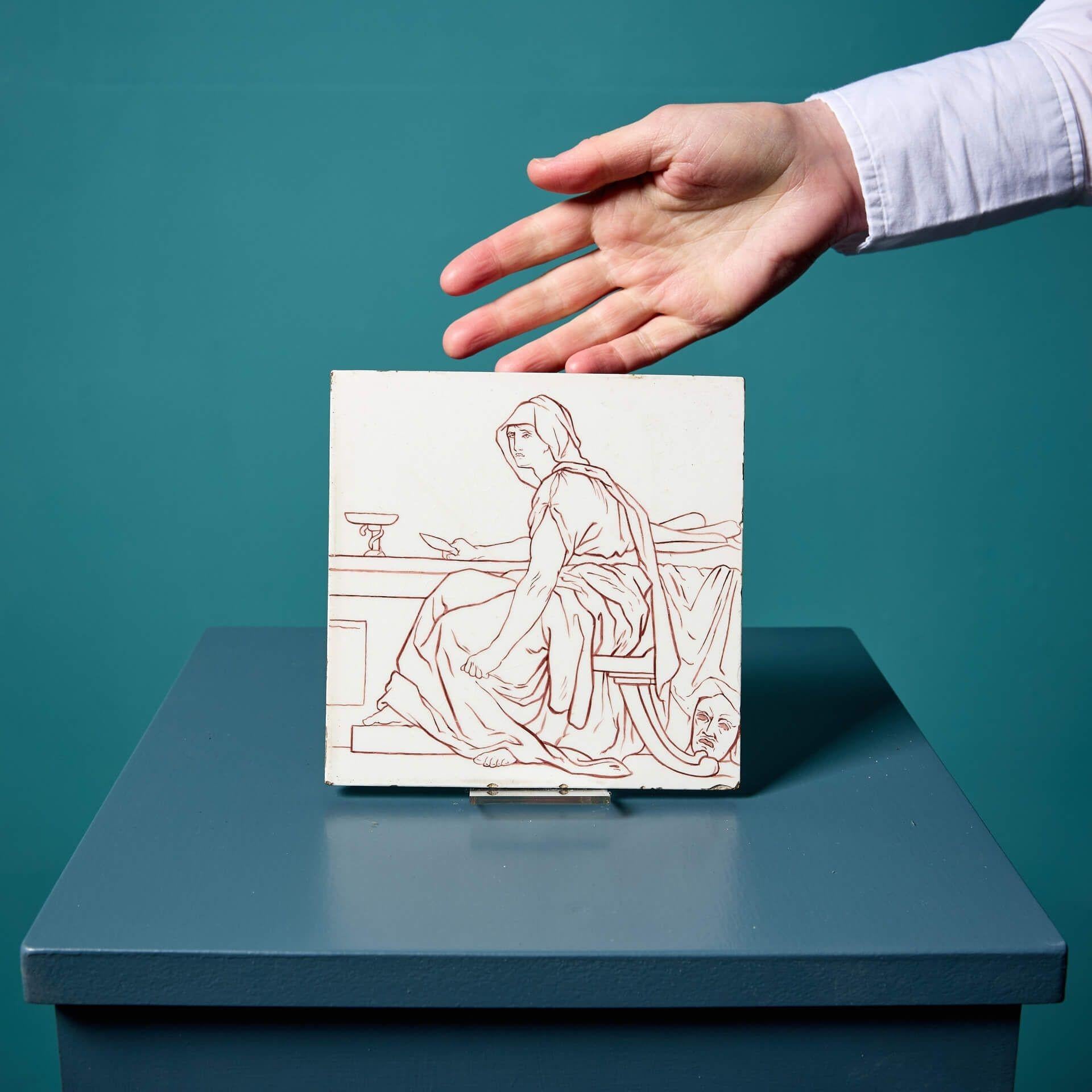 Un rare carreau émaillé ancien de 6 pouces de Doulton and Co. de Lambeth (estampillé) représentant une figure néoclassique encapuchonnée symbolisant la Tragédie.


Dans ce dessin simple, la figure assise se dessine en manganèse sur un fond blanc,