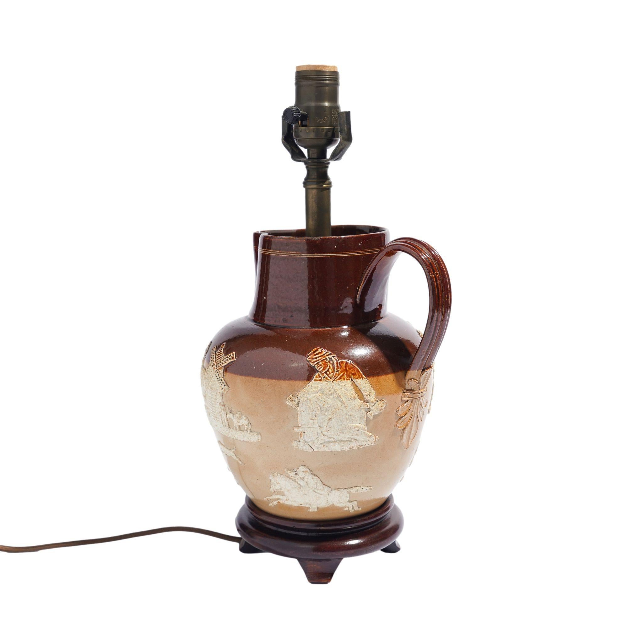 Doulton glazed stoneware pitcher, mounted as a lamp on a wood base.
England, circa 1900.

Dimensions: 8” L x 7” W x 15” H (to top of socket)