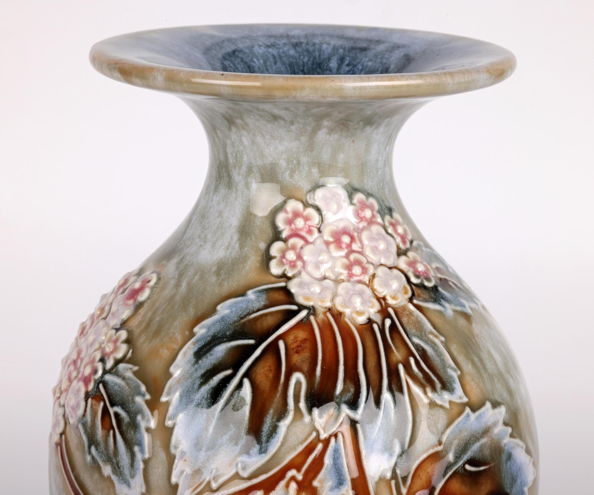 A stunning Doulton Lambeth Art Nouveau stoneware vase decorated with floral designs by renowned artist Florence C Roberts and dating from around 1905. The tall elegantly shaped vase stands raised on a narrow round skirted foot with a tall bulbous