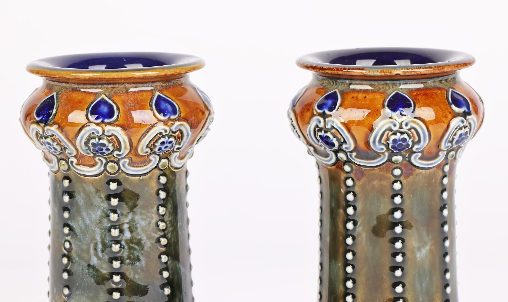 A very stylish pair Doulton Lambeth Art Nouveau bud shaped vases with stylized floral designs by Ethel Beard and Rosina Harris and dating from around 1902. The stunning pair stone ware vases stand on a wide skirt shaped foot with a funnel shaped