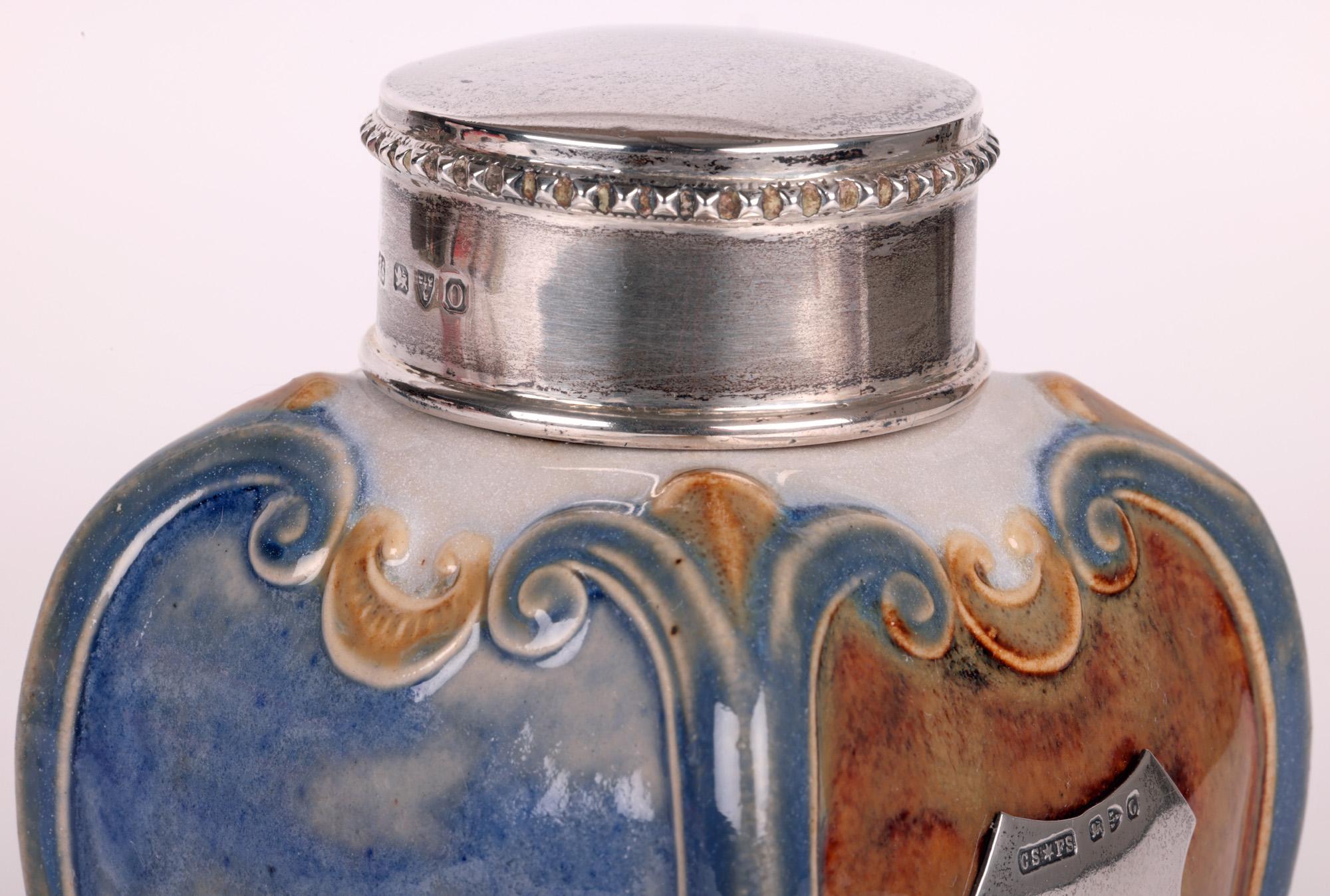 A very stylish and unusual Doulton Lambeth Art Nouveau silver mounted mottoware tea caddy by renowned artist Eleanor Tosen and dating from around 1897. The square and elegantly shaped stoneware tea caddy stands on a skirted square foot with unglazed