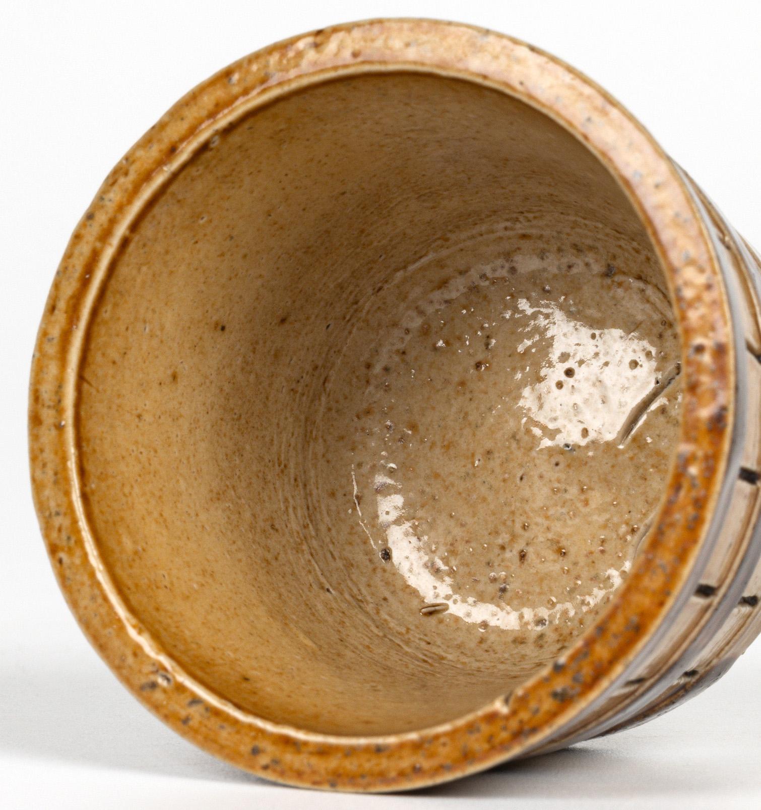 Rara y temprana sal de Doulton Lambeth con forma de cubo y fechada en 1876. La sal de gres tiene forma de cubo pequeño, redondeado y ligeramente cónico, formado por tablones de madera sujetos con bandas de fleje. La sal está decorada con un esmalte